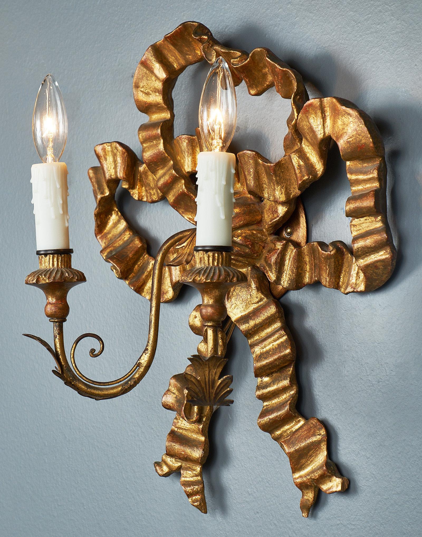A pair of antique Louis XVI style gold bow sconces from France. Each piece features a 23-carat gold leafed neoclassical finely detailed bow and two gold leafed arms with candlelight sockets, rewired to US standards.