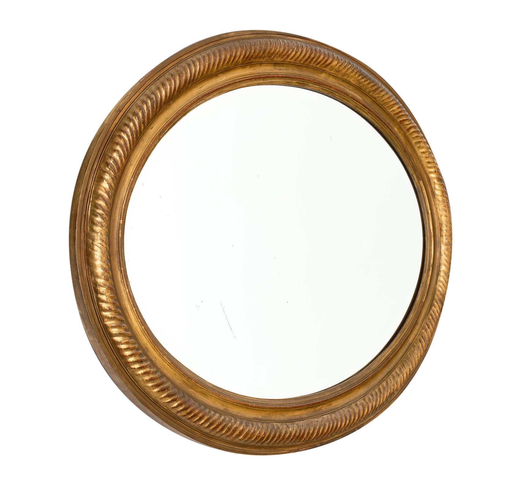 Louis XVI style antique oval mirror with a beautiful gold-leafed and ridged frame. We love the original mirror with beveled edge and the strong presence this piece has. This mirror is from the south of France and has a lovely authenticity.