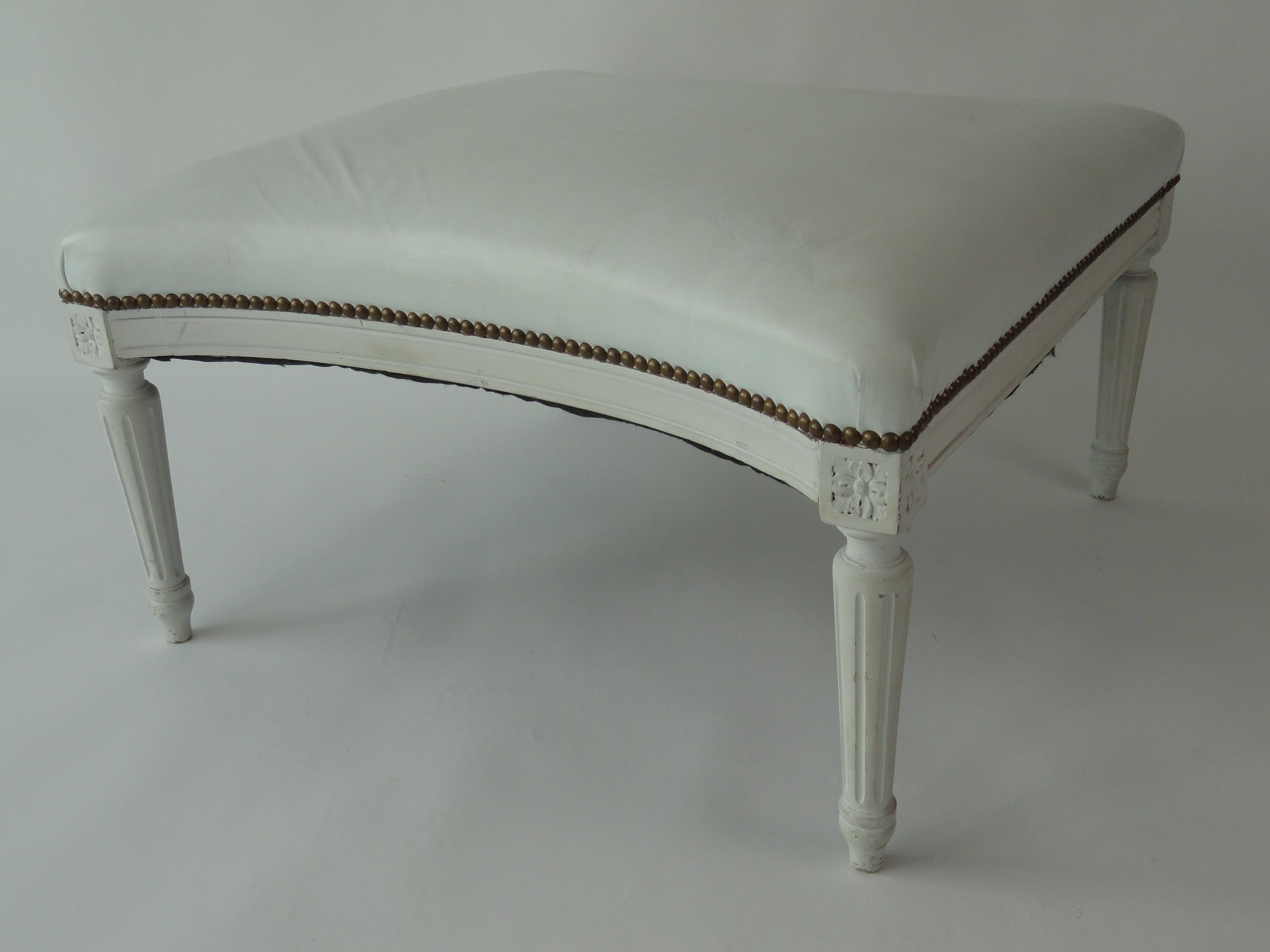 Louis XVI style bench made of carved wood and covered in white leather with brass nail heads.
      