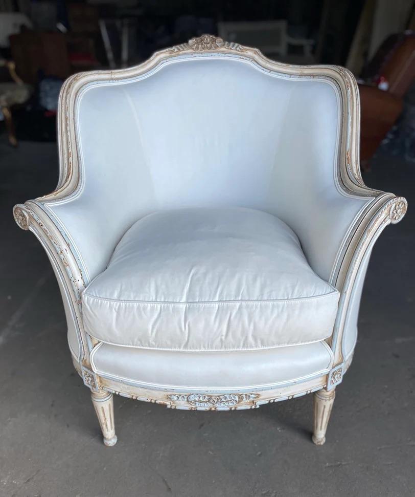 Here is a beautiful and feminine pair of Louis XVI style bergere chairs. The color palette is a light blue/gray with ivory color paint through the trim with the patina and natural wood showing through in various places with chipped paint. The