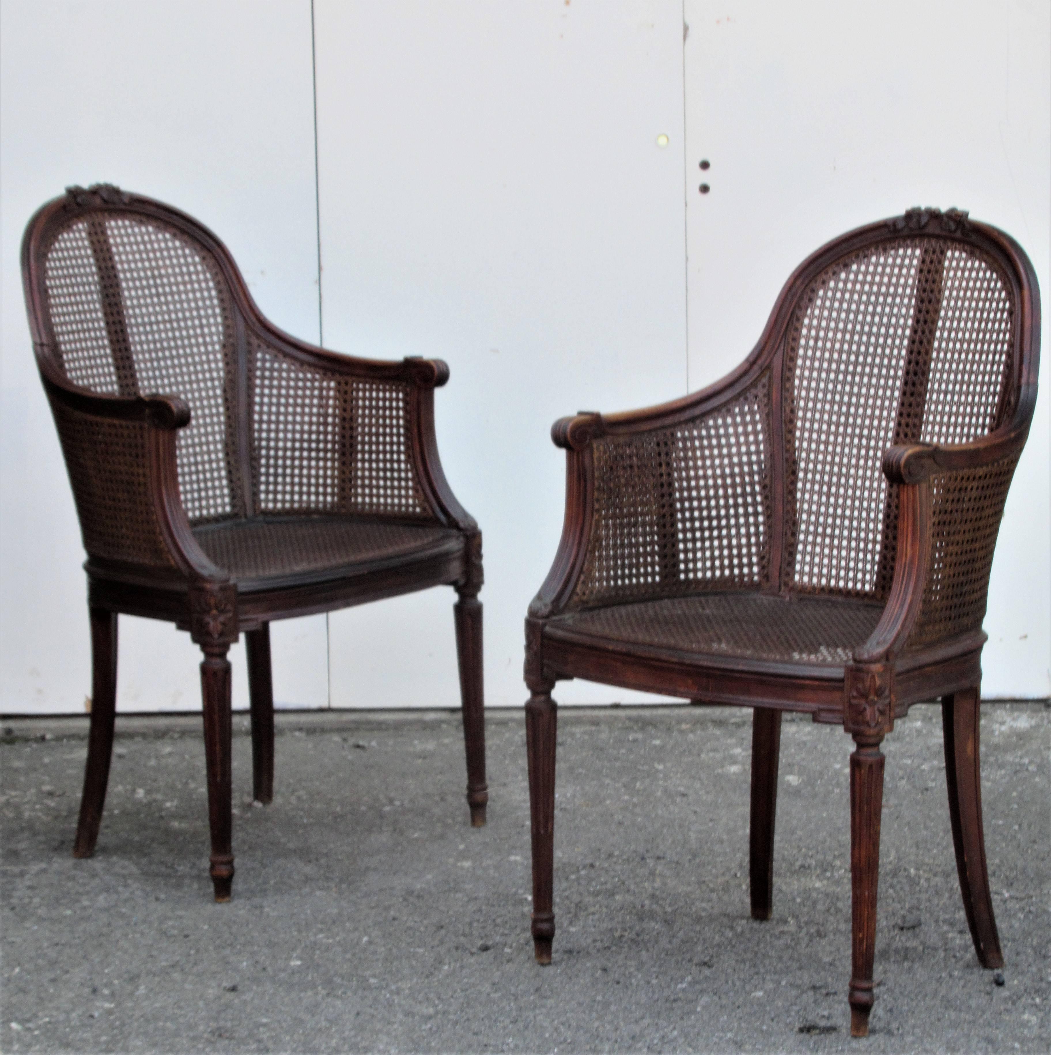 Pair of finely carved Louis XVI style bergere chairs with original caning and perfectly aged rich color patina to wood and cane. We think they are beechwood. Circa 1920-1940.