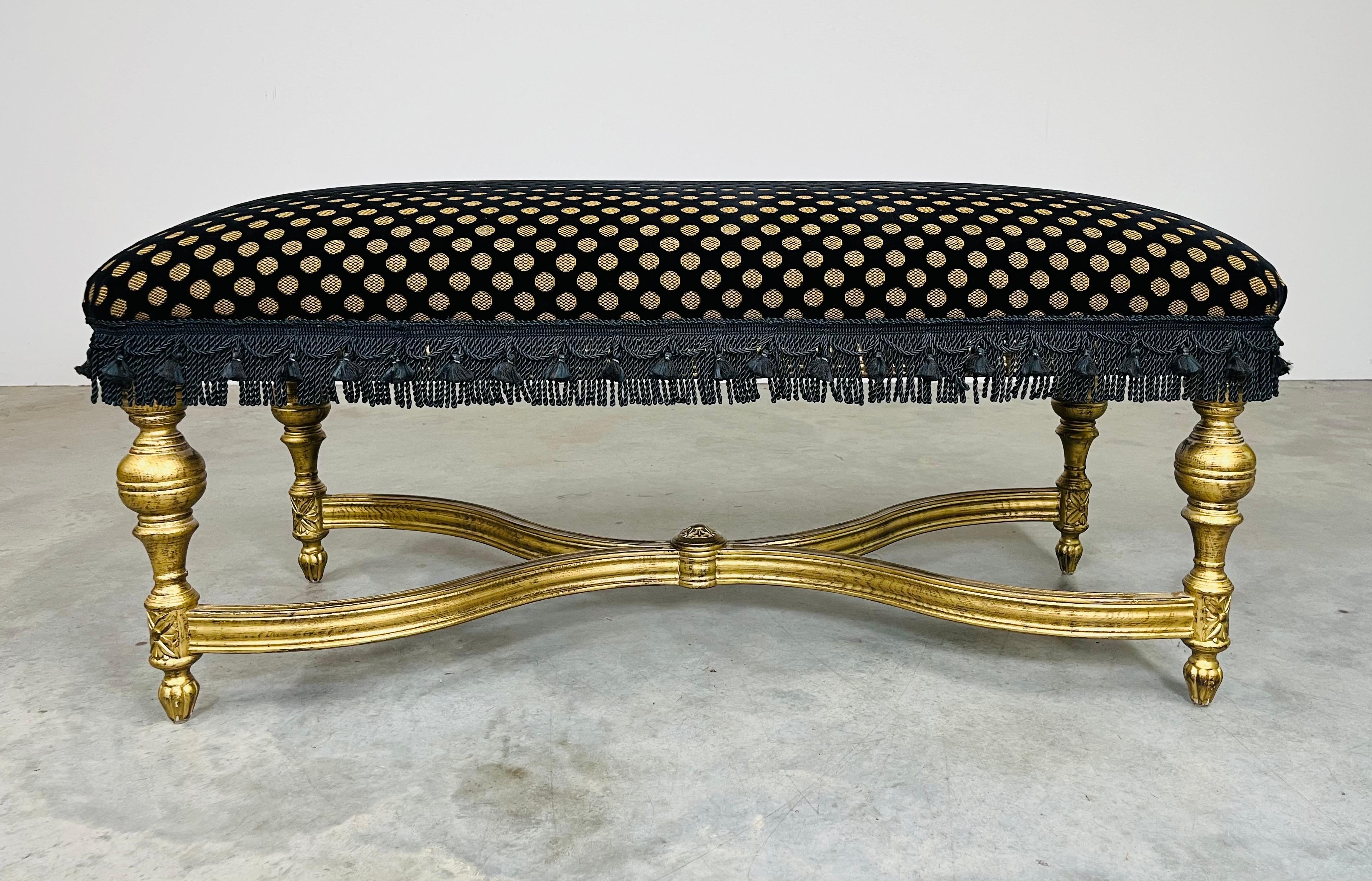 Banc de style Louis XVI, doré à l'or fin, recouvert de mohair noir avec un motif concave de pointillés dorés, bordé de pompons noirs satinés, sur un superbe châssis en X, doré à l'or fin, avec des pieds tournés. 
En excellent état, elle a servi de