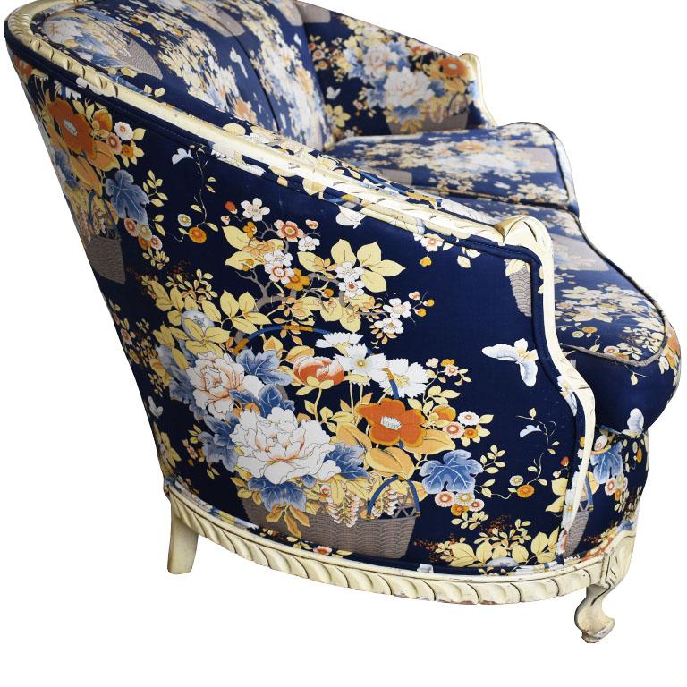 Floral Louis XVI style sofa in blue. The seat back of this beauty is framed in a carved wood detail around the edges. At the top, a cream wooden cartouche curls down to surround the entire top of the sofa down to the arms. The base rests on six
