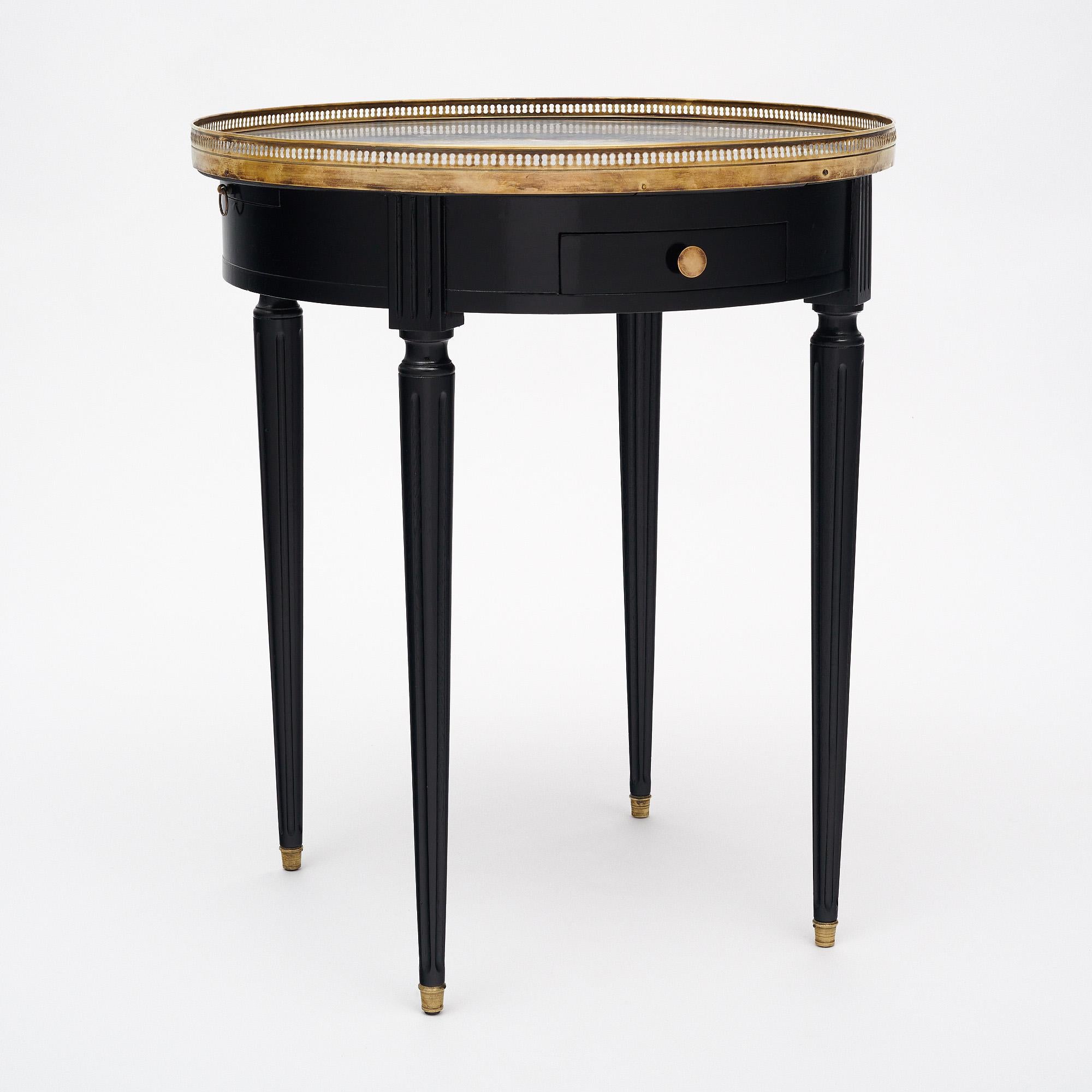 Side table from France made of mahogany that has been ebonized and finished in a lustrous museum-quality French polish. A Saint Anne marble top is surrounded by a brass gallery (restored). There are two dovetailed drawers and two leaf pull outs