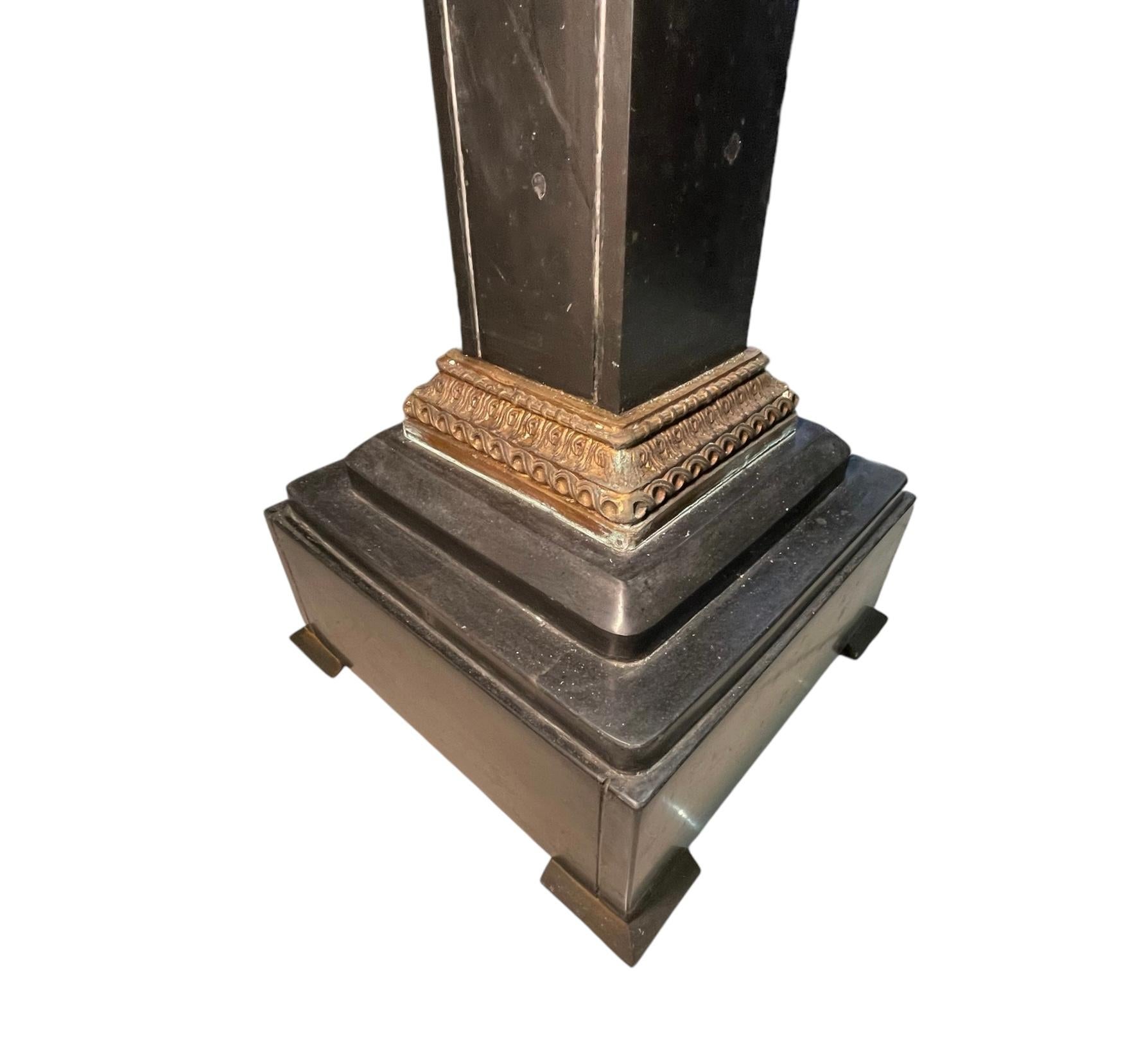 Dies ist ein Louis XVI-Stil schwarzer Marmorsockel. Es zeigt eine große quadratische schwarze Marmorplatte, die von einer dreidimensionalen rechteckigen Marmorsäule getragen wird, die auf einem drei Stufen breiten quadratischen Sockel befestigt ist.