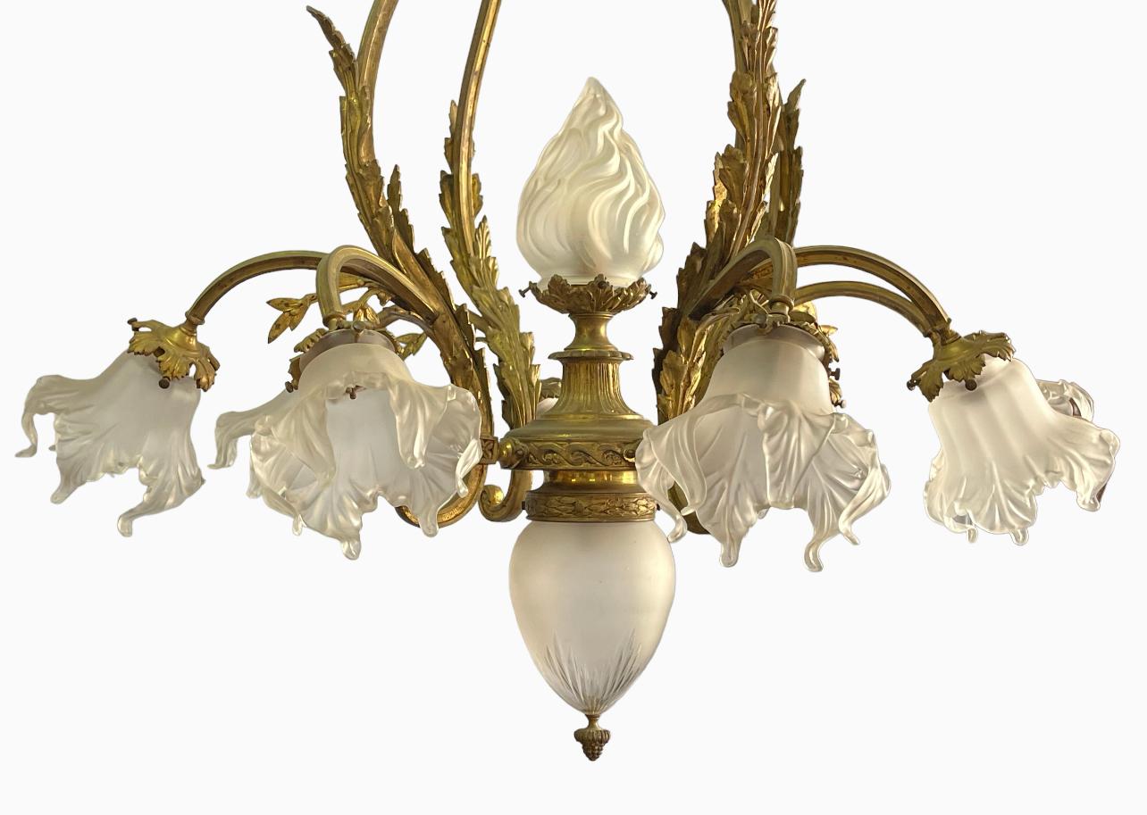 Important Louis XVI style gilded bronze chandelier with 11 lights. It is composed of 8 arms of light with tulips as well as a globe in the shape of a shell and a large flame. Complete and entirely original. Very good state. Electrification to be