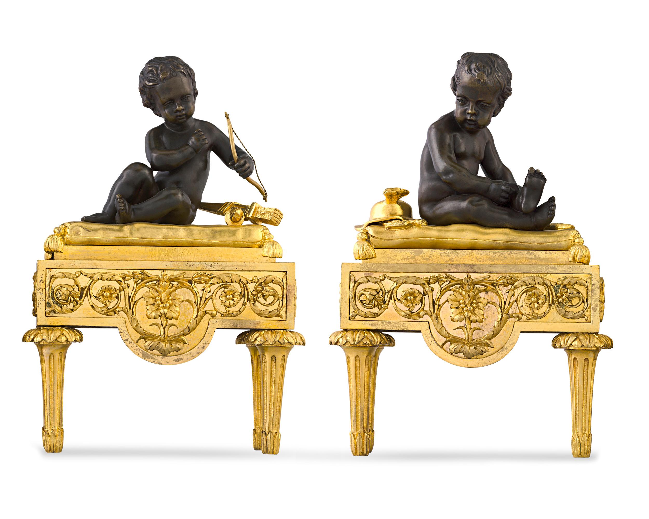 Cherubs representing the gods Cupid and Mercury, indicated by their respective bow and winged helmet, sit atop this charming pair of French chenets, or fireplace andirons. Crafted of stunning doré and patinated bronze, these figures display a