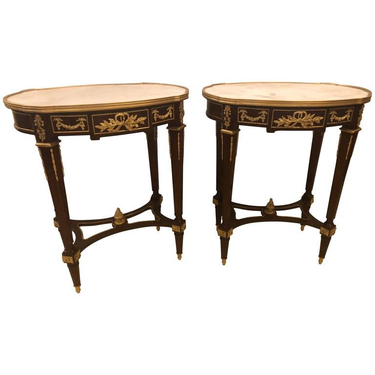 Louis XVI style doré bronze framed marble-top end or lamp table with bronze mounts. The white Carrara marble top with grey veins supported by a set of tapering bronze fluted square legs each having an X-base undercarriage with a bronze finial in the