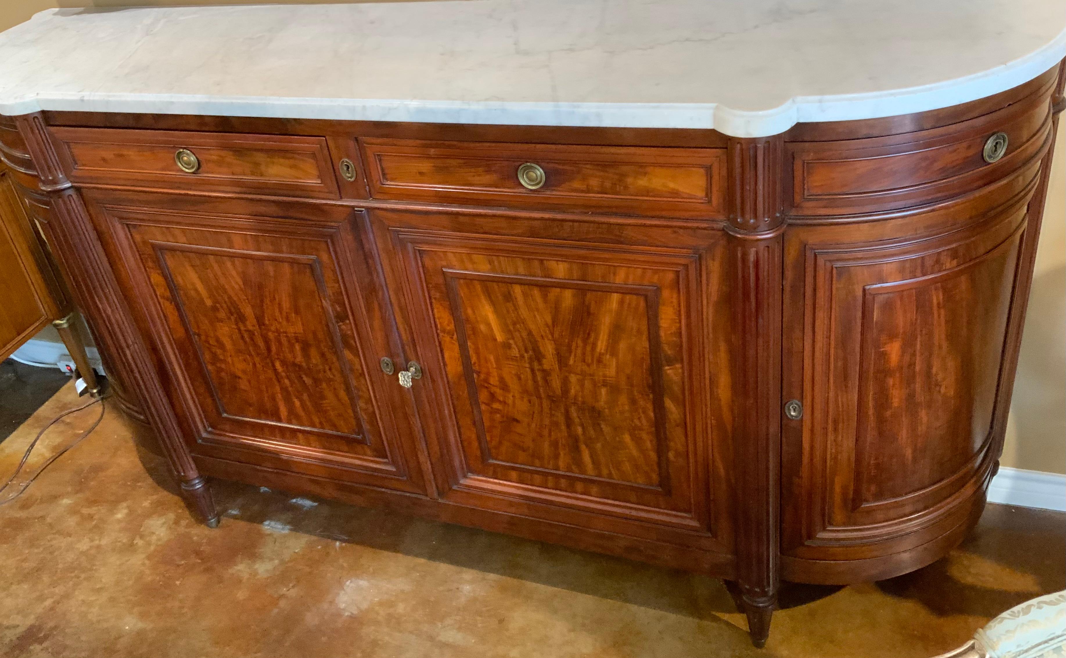 Fine mahogany wood has been used in construction of this piece.
A white marble top with very light gray veining is on top and has
No breaks or restorations. It has graceful curved sides. All doors and
Drawers open and slide easily. It has a key and