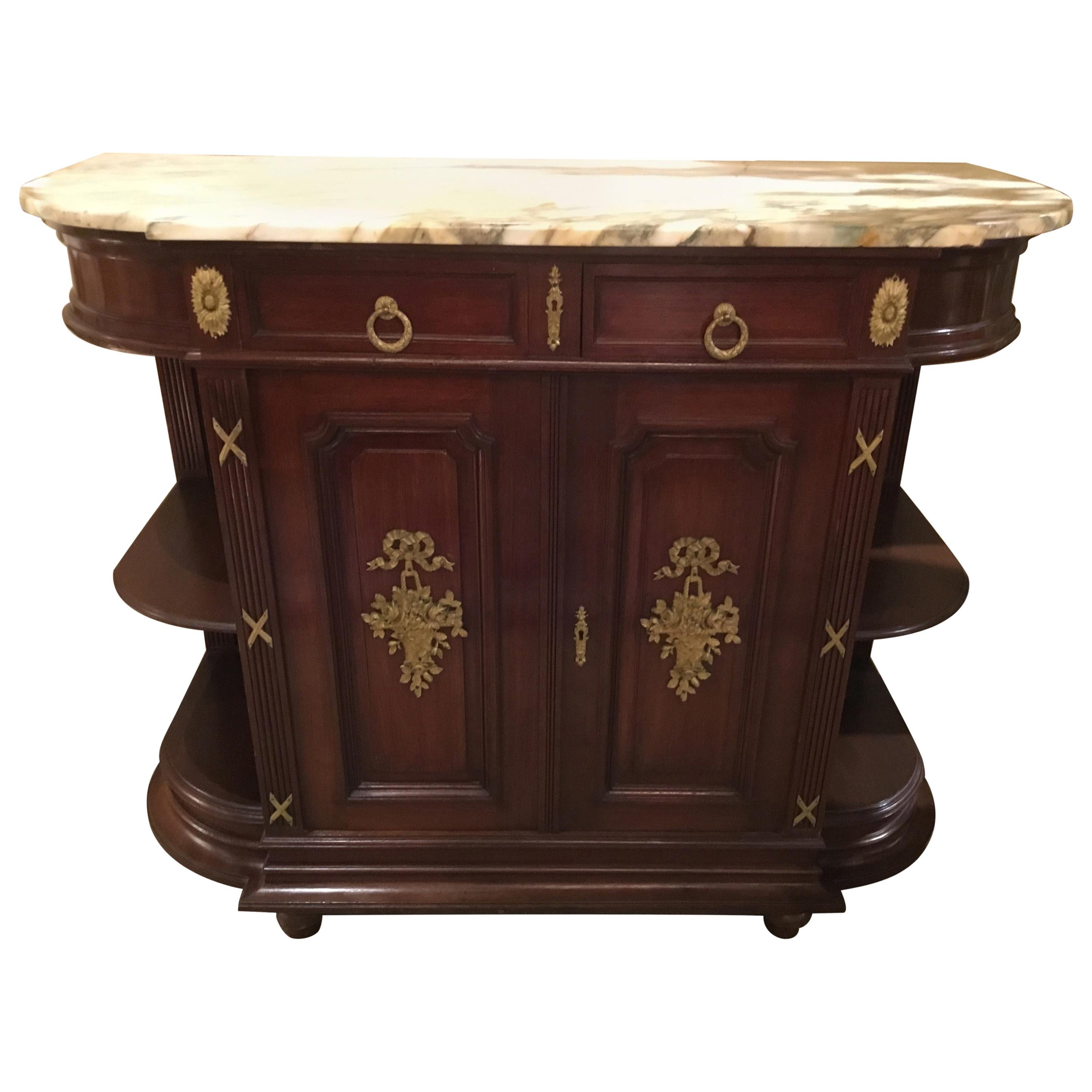 Walnut buffet in walnut with gilt bronze mounts depicting a basket with
Floral and foliate designs and topped by a bow. A cream marble top 
With shades of gray and is over two drawers. Two doors open to
Storage with one shelf. The cabinet is in a