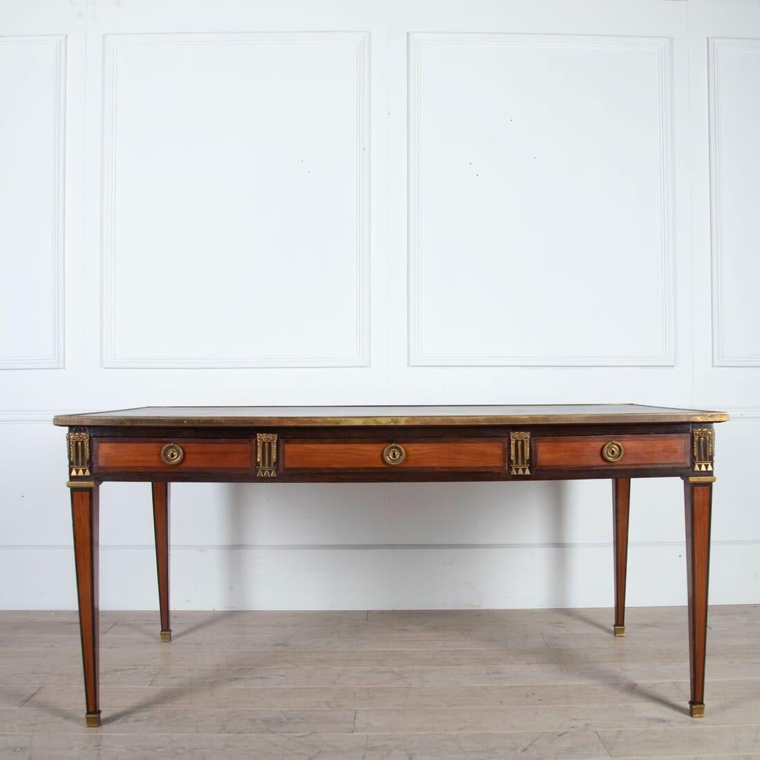 An early 20th century French bureau plat in Louis XVI style with brass-bound tooled leather top and well cast brass mounts.