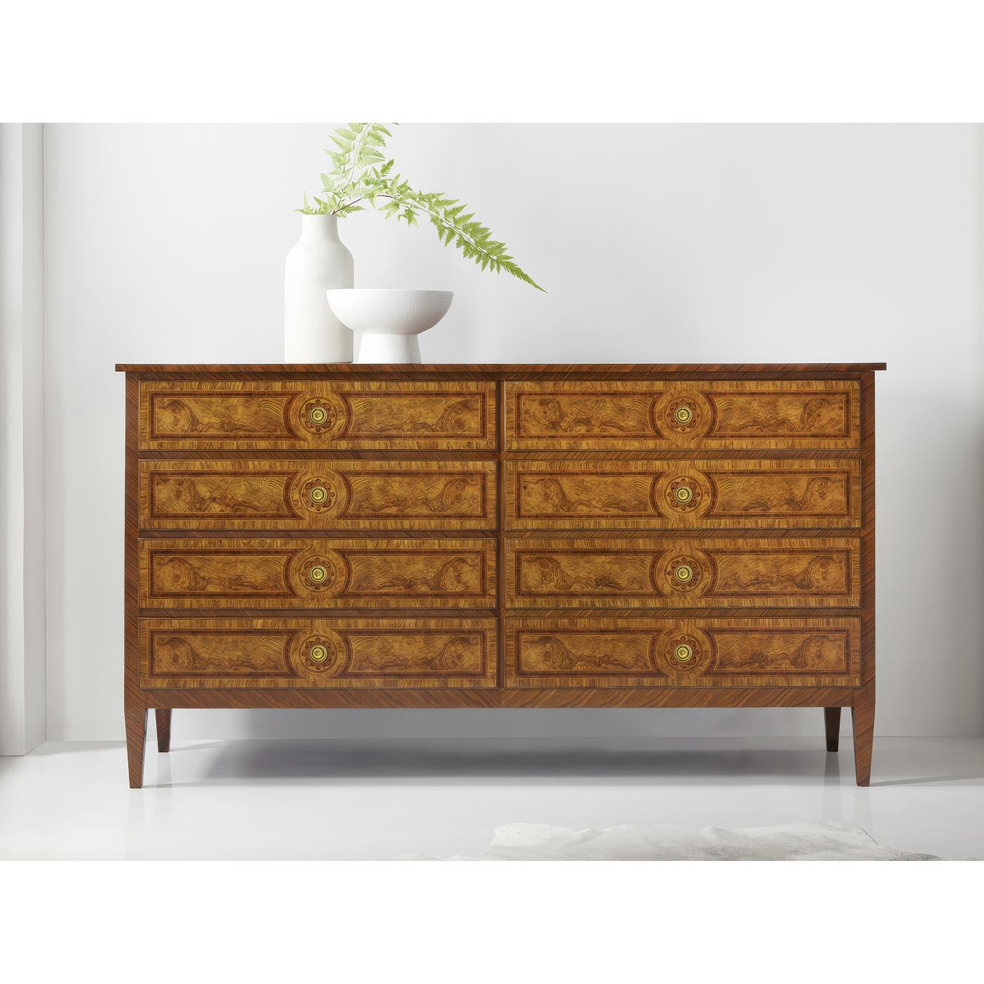 Il comò incarna la raffinata eleganza del design francese del XVIII secolo grazie all'uso magistrale di impiallacciature di radica e delicati intarsi. Tutti i frontali dei cassetti presentano motivi di radica disposti simmetricamente e incorniciati