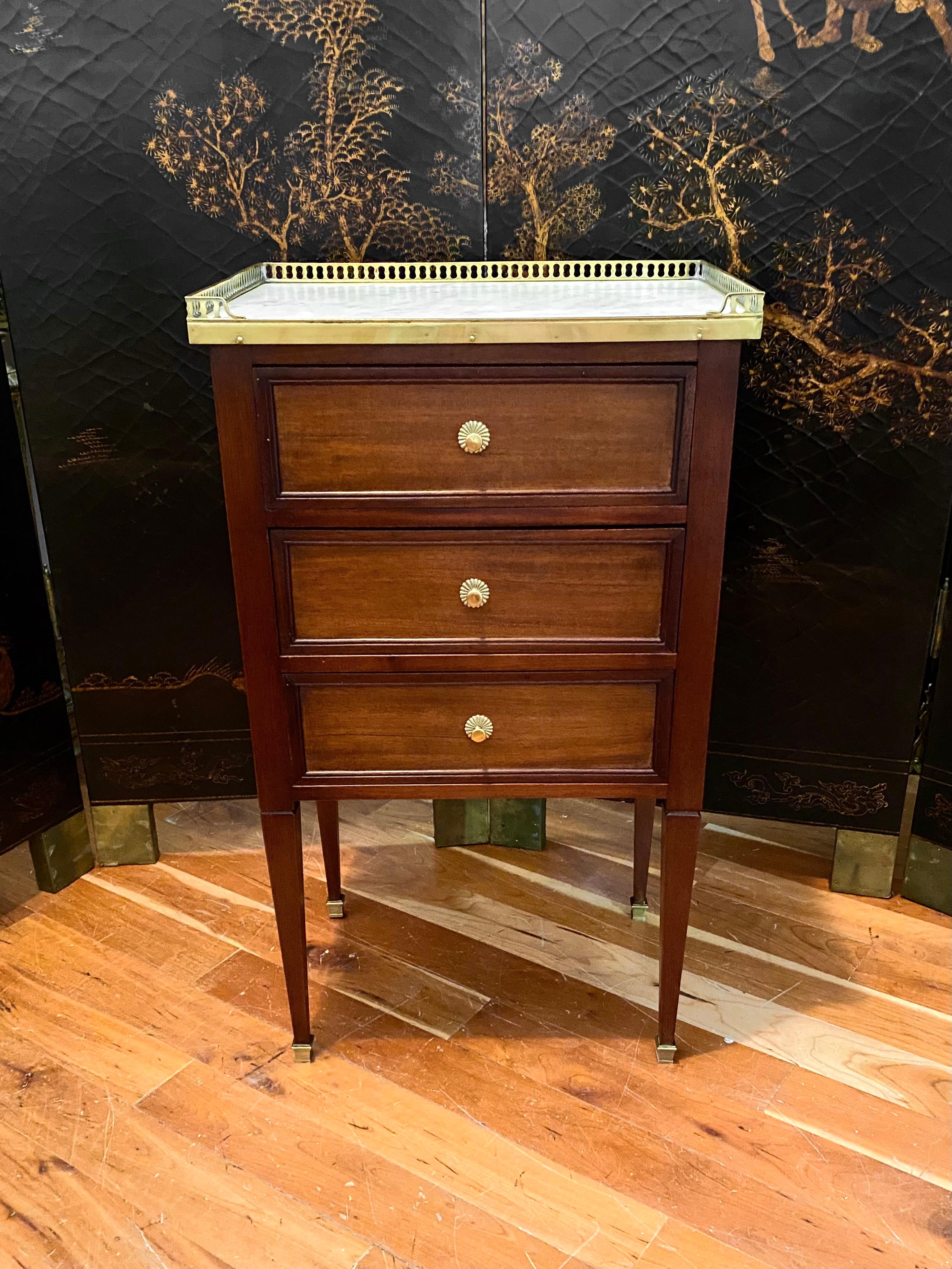 Louis XVI Style cabinet or commode chest of drawers style nightstand with marble top and bronze gallery. 
White marble top surrounded by a bronze pierced gallery. The cabinet is fronted by three drawers. It is mounted on four Louis XVI Style legs