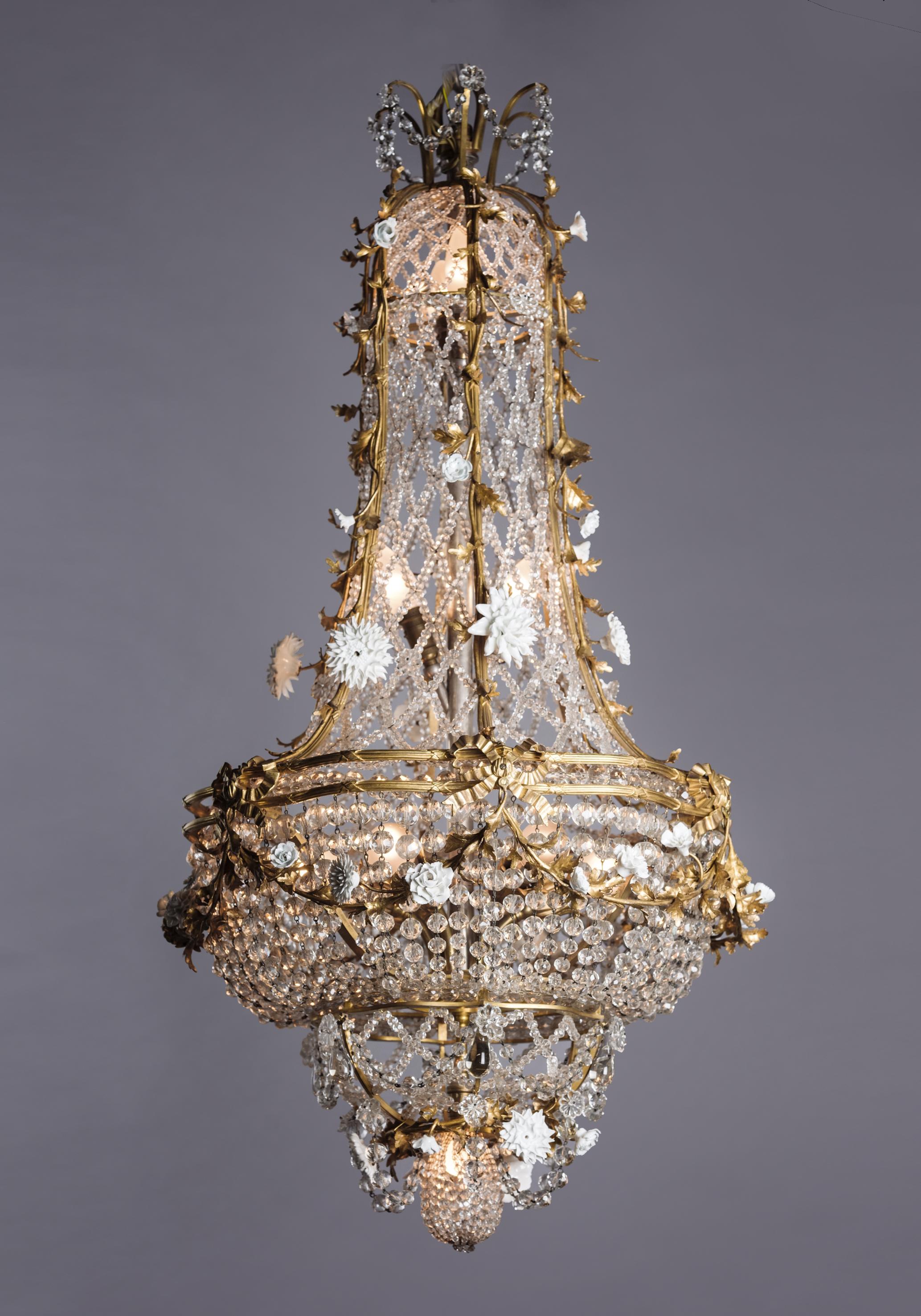 A fine Louis XVI style gilt-bronze and glass cage chandelier with applied porcelain flowers, attributed to L'Escalier de Cristal.

French, circa 1900. 

Fitted internally with eleven light fitments. 

This fine chandelier is of cage form with