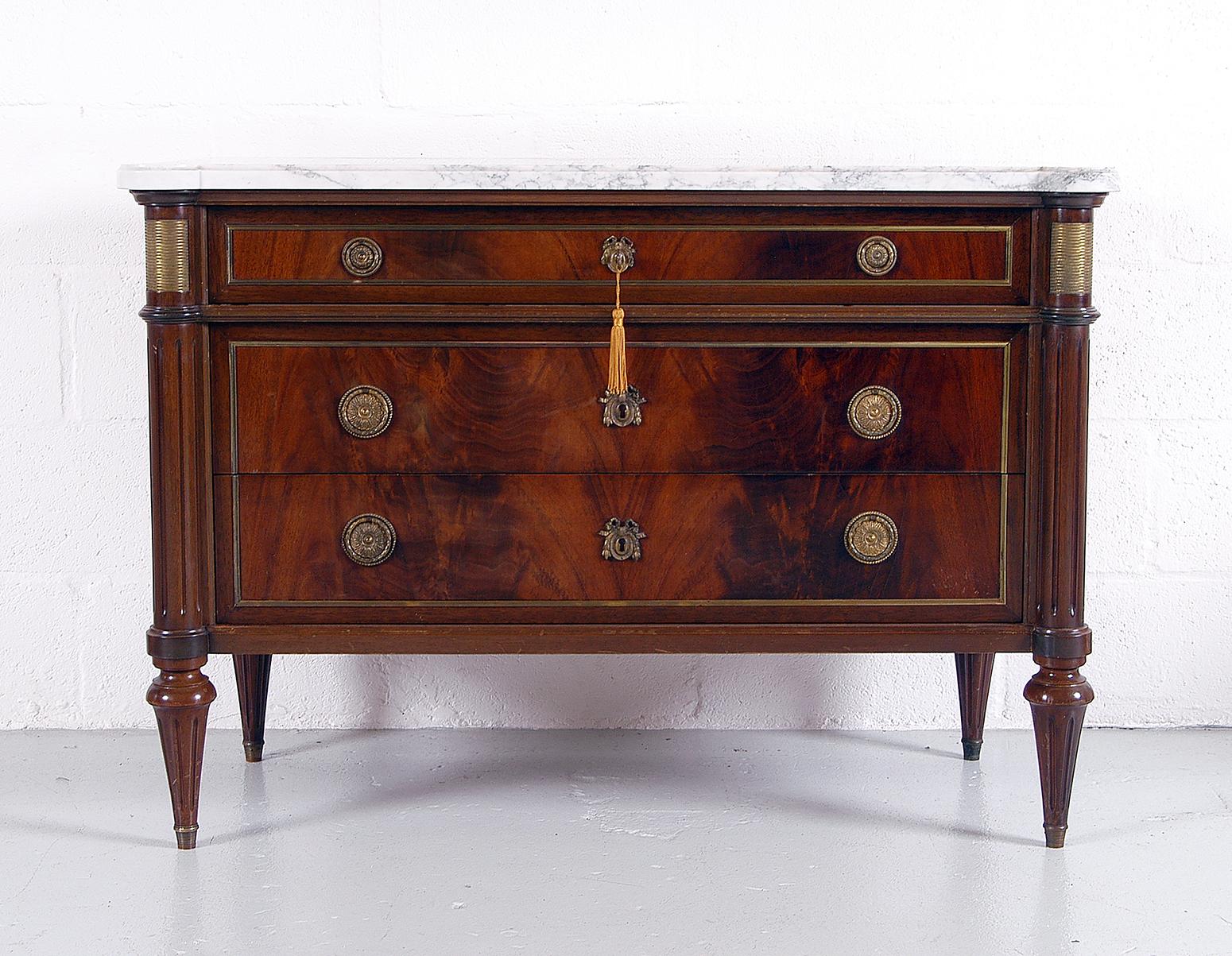 A lovely 20th century French walnut commode made in the Louis XVI style. 
The simple fielded drawers are edged with brass and fitted with brass drop ring pulls on backplates. Faux escutcheons on the bottom two drawers as only the top drawer is