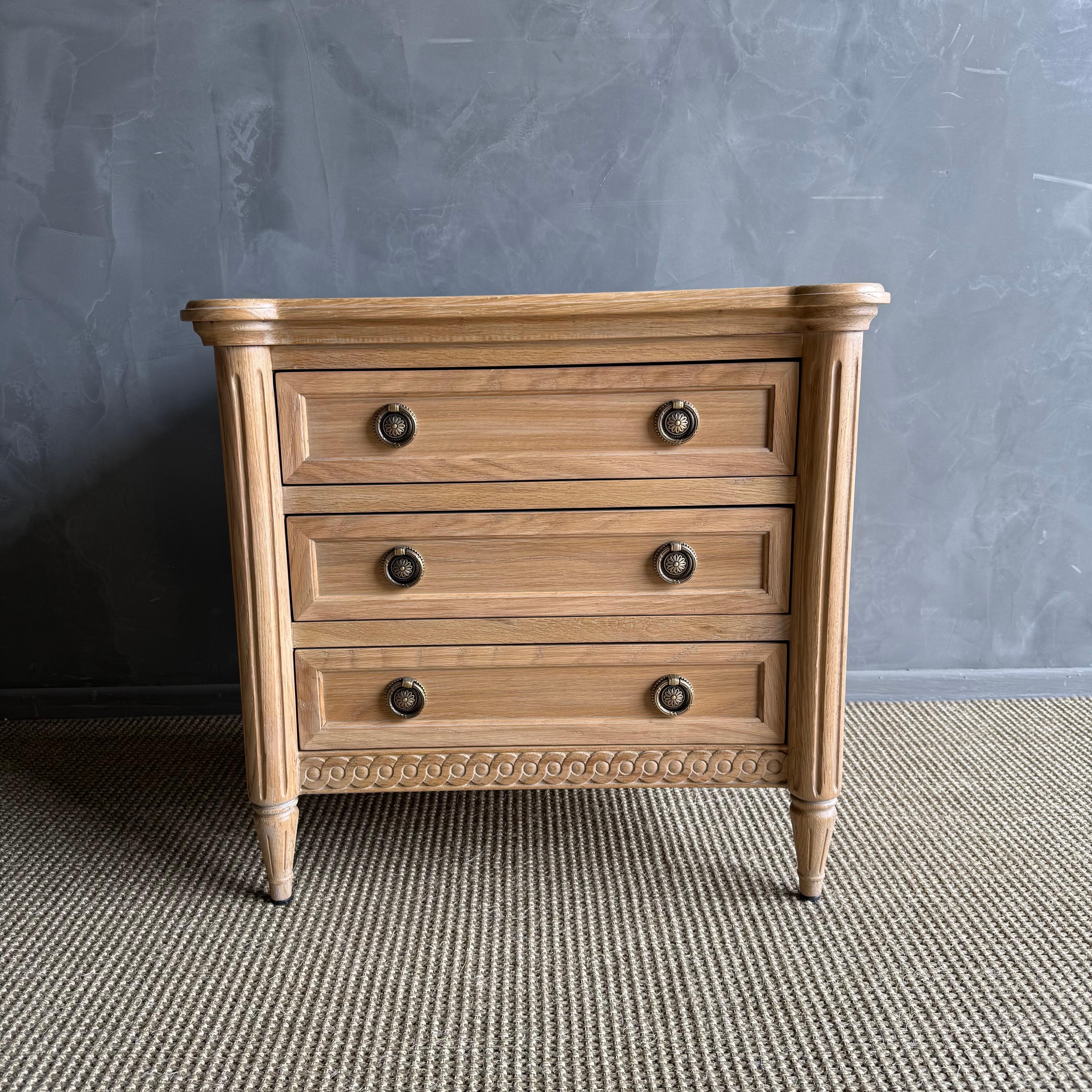 Louis XVI style 3 drawer nightstand in a beautiful natural white oak finish. The elegant design of this Louis XVI nightstand features intricate detailing and craftsmanship that exudes luxury and sophistication. With three soft close drawers, this