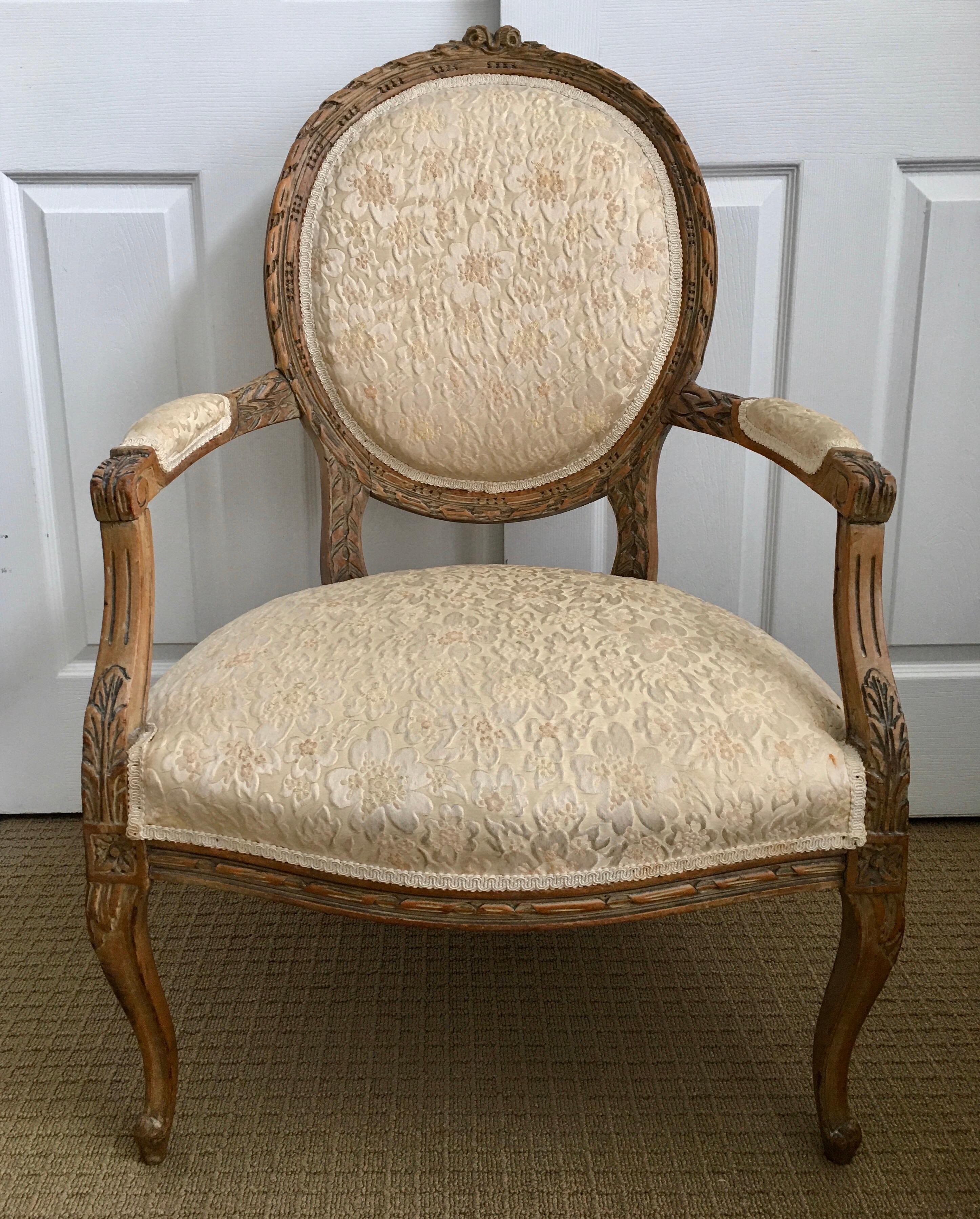 Mid-20th century Louis XVI style natural wood carved fauteuil armchair. This oval back chair features beautifully carved acanthus leaf appointments and cabriole legs. A beautiful bedroom or living room accent chair. 

Measures: Inside seat depth