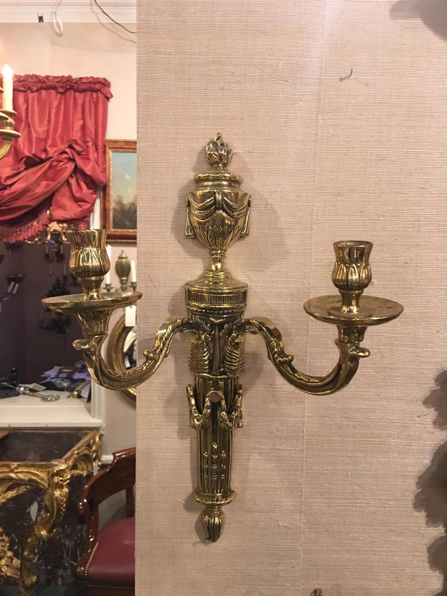 Louis XVI style cast patinated brass two-candle sconce with intricate details of flames and foliage throughout, scrolled arms lead to bobeches, 19th century. Professionally polished.