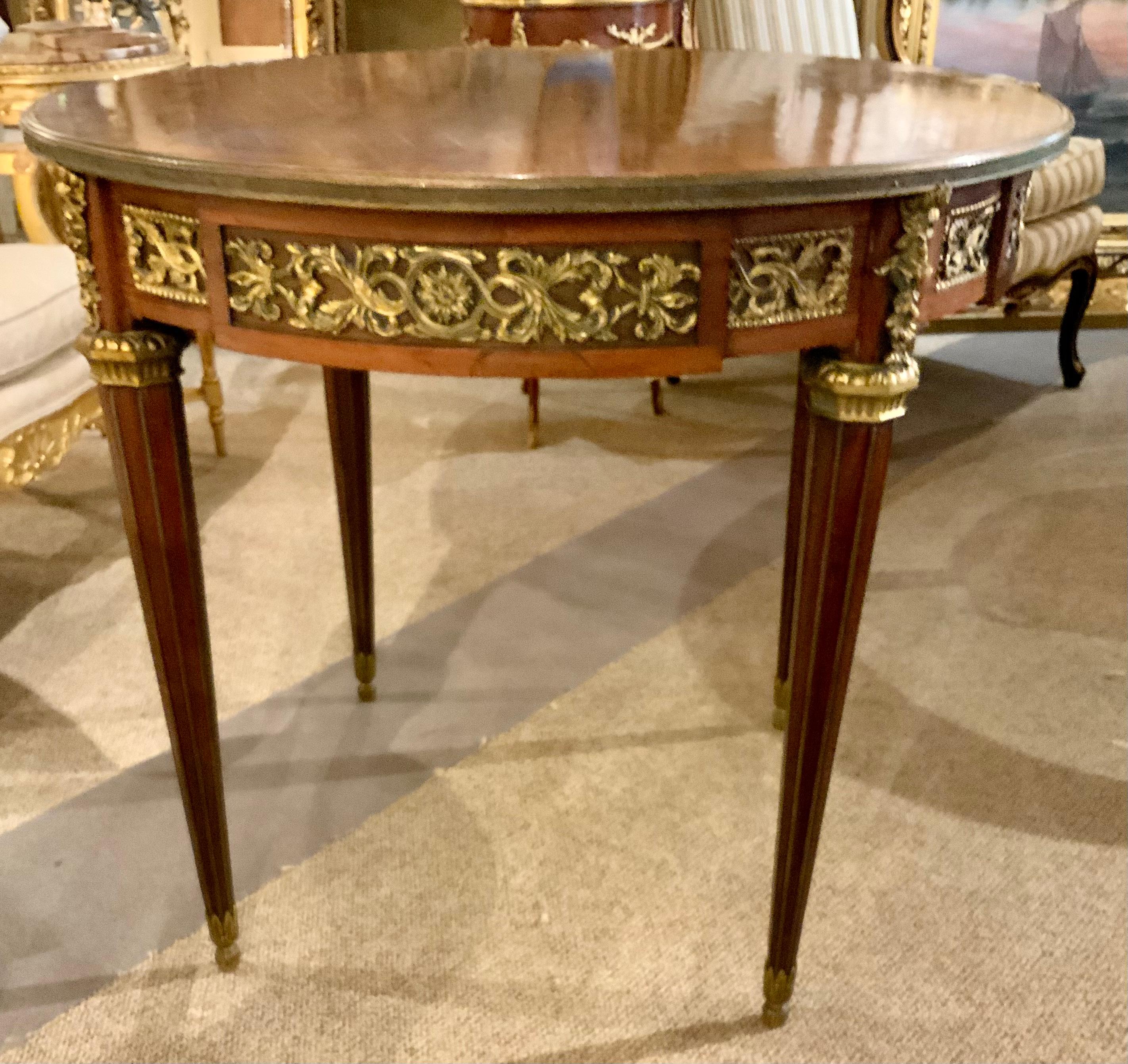 This kingwood center table is in the Louis XVI-Style. The patterned-parquetry 
Circular top is within a circular band, above a conforming patterned frieze
Fitted with a single drawer and with applied foliate ormolu patterns, raised
On tapering