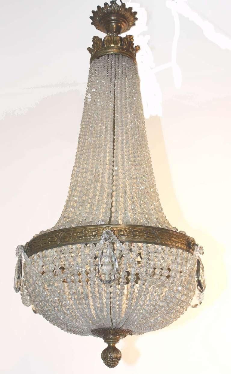 Louis XVI-Stil  Kronleuchter aus Bronze und Kristall, ausgestattet mit fünf Innenleuchten. Abgestufte Perlengirlanden verbinden die Anthemion-Krone mit dem zentralen Band, von dem ein halbkugelförmiger Korb mit einem Eichelknopf in der Mitte