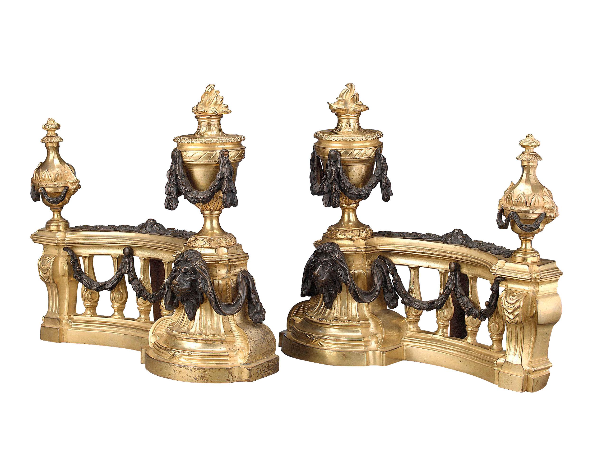 This superb pair of Louis XVI-style chenets, or andirons, is crafted of solid doré bronze and adorned with swags and lion heads of patinated bronze, circa 1840 15 1/2” wide x 14 1/2” high.