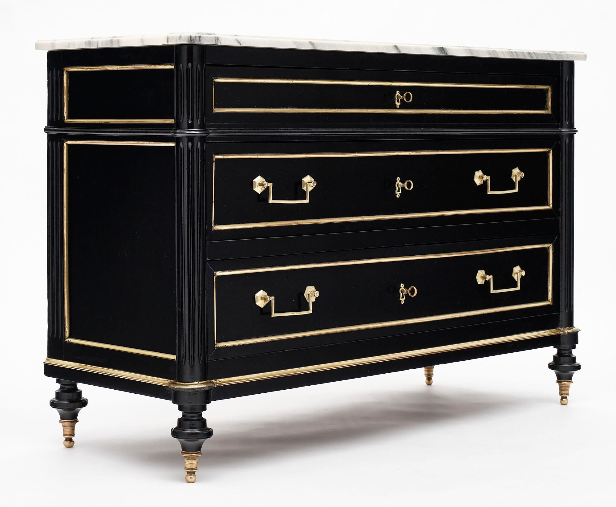 Louis XVI style chest of drawers from France made of mahogany that has been ebonized and finished with a lustrous museum-quality French polish. We love the toupies legs and intact Carrara marble top. There is gilt brass trim throughout.