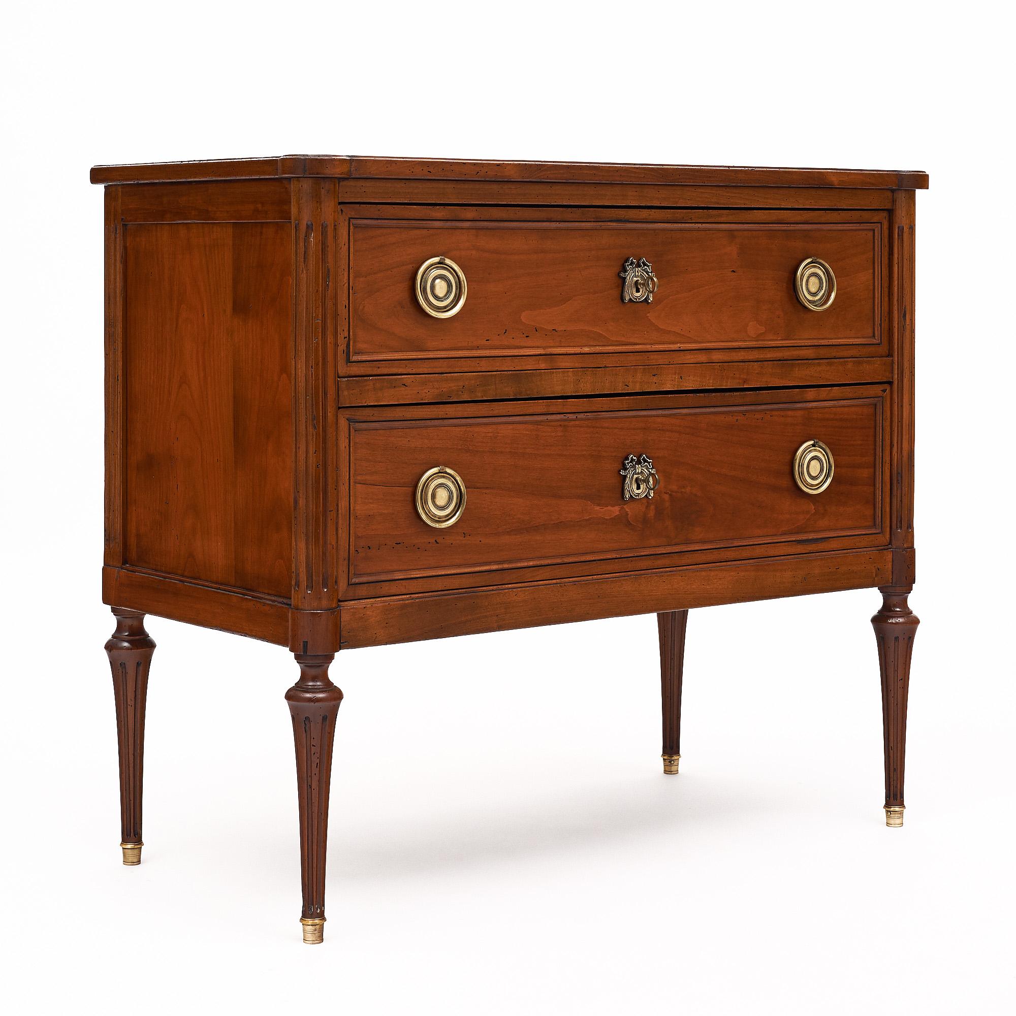 Petite chest of drawers from France in the Louis XVI style. This piece is made of cherry wood that has been finished with a lustrous French polish of museum quality. There are two dovetailed drawers with original cast brass hardware and locks. The