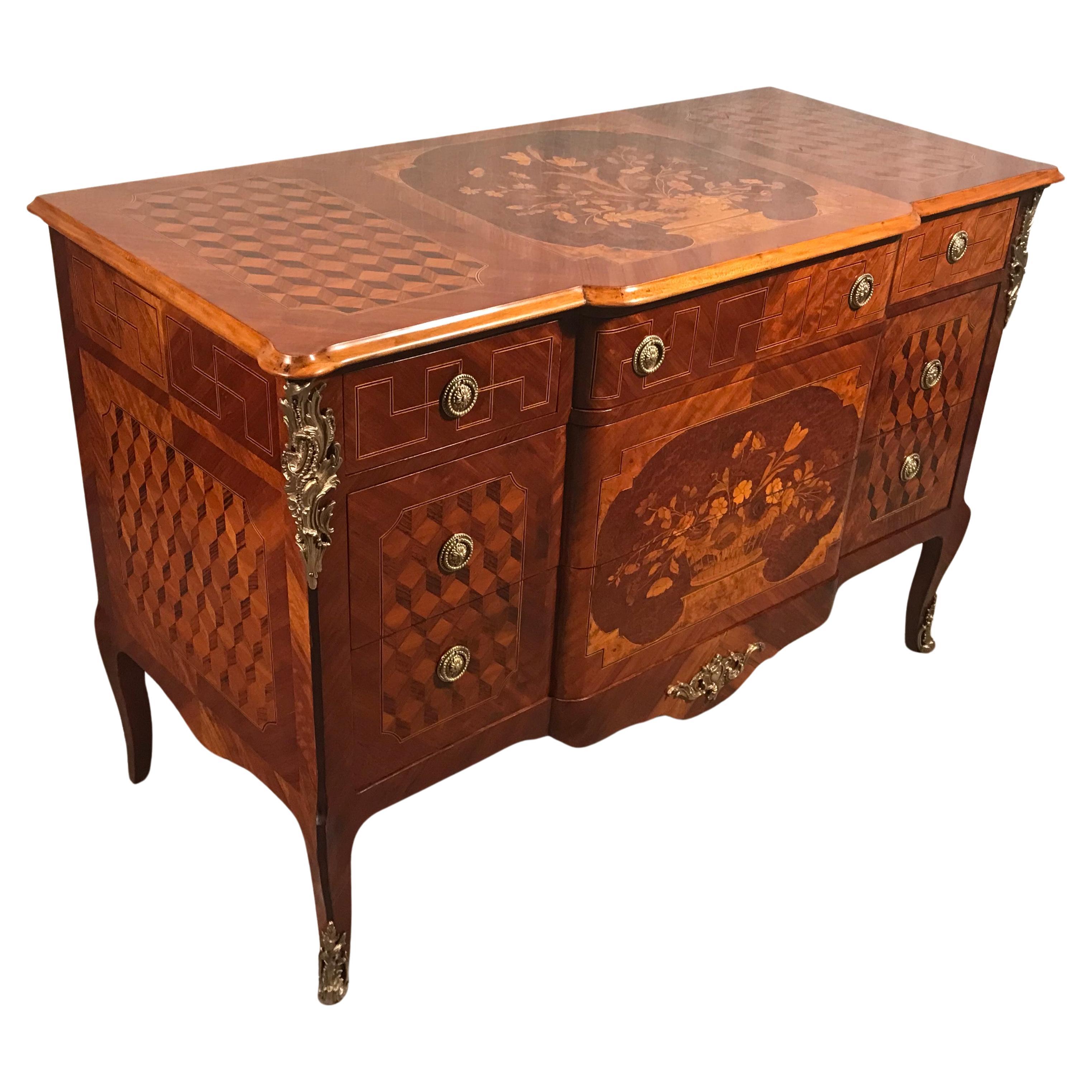 This remarkable chest of drawers, boasting the elegant Louis XVI Style, dates back to the late 19th century. Comprising five drawers, this commode features exquisite marquetry work that truly captivates the eye. The central portion of both the front
