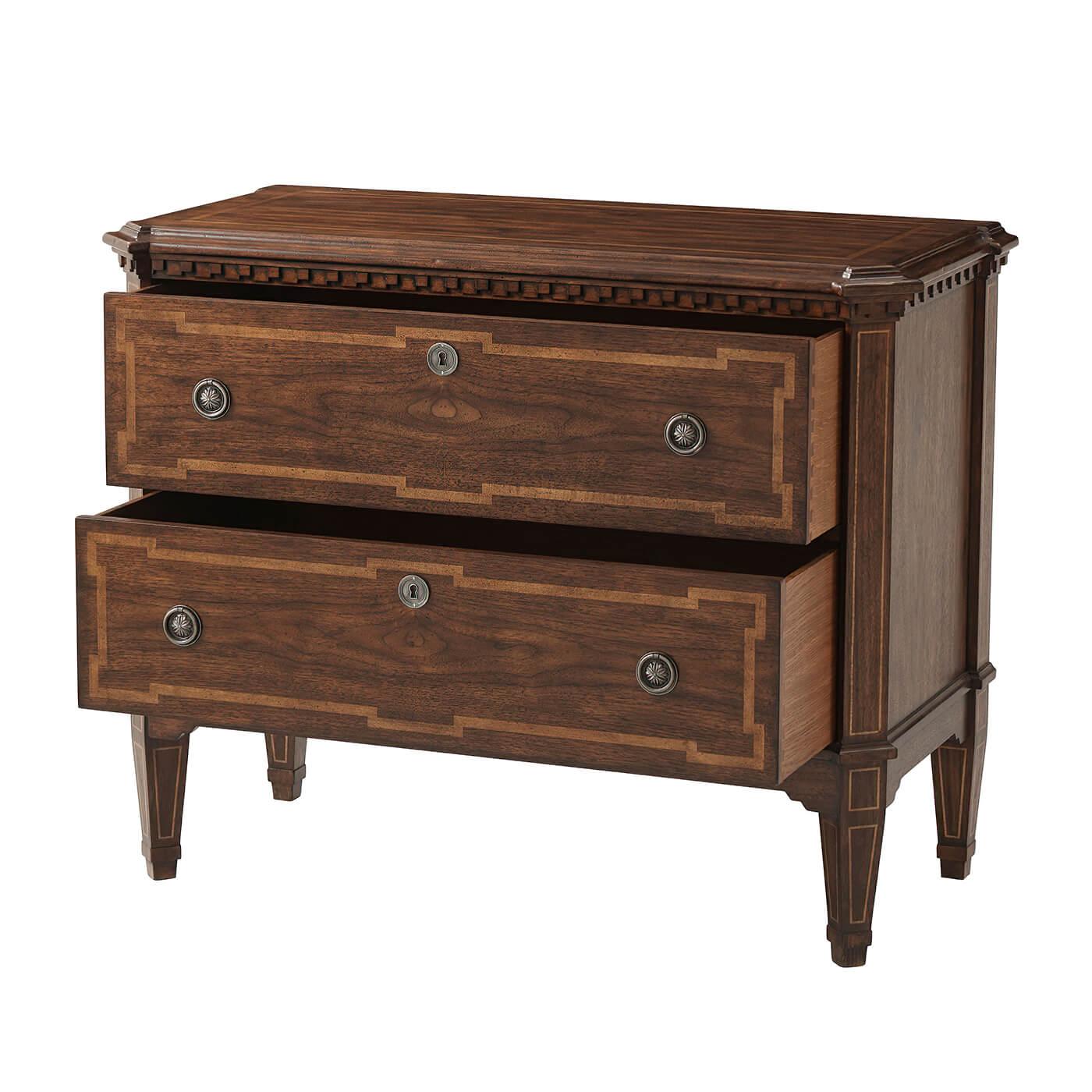A European Louis XVI style commode with a molded edge top with canted corners, carved dental molding frieze above two long drawers with panel inlays, antiqued pewter handles and square tapered and inlaid legs.

Dimensions: 40