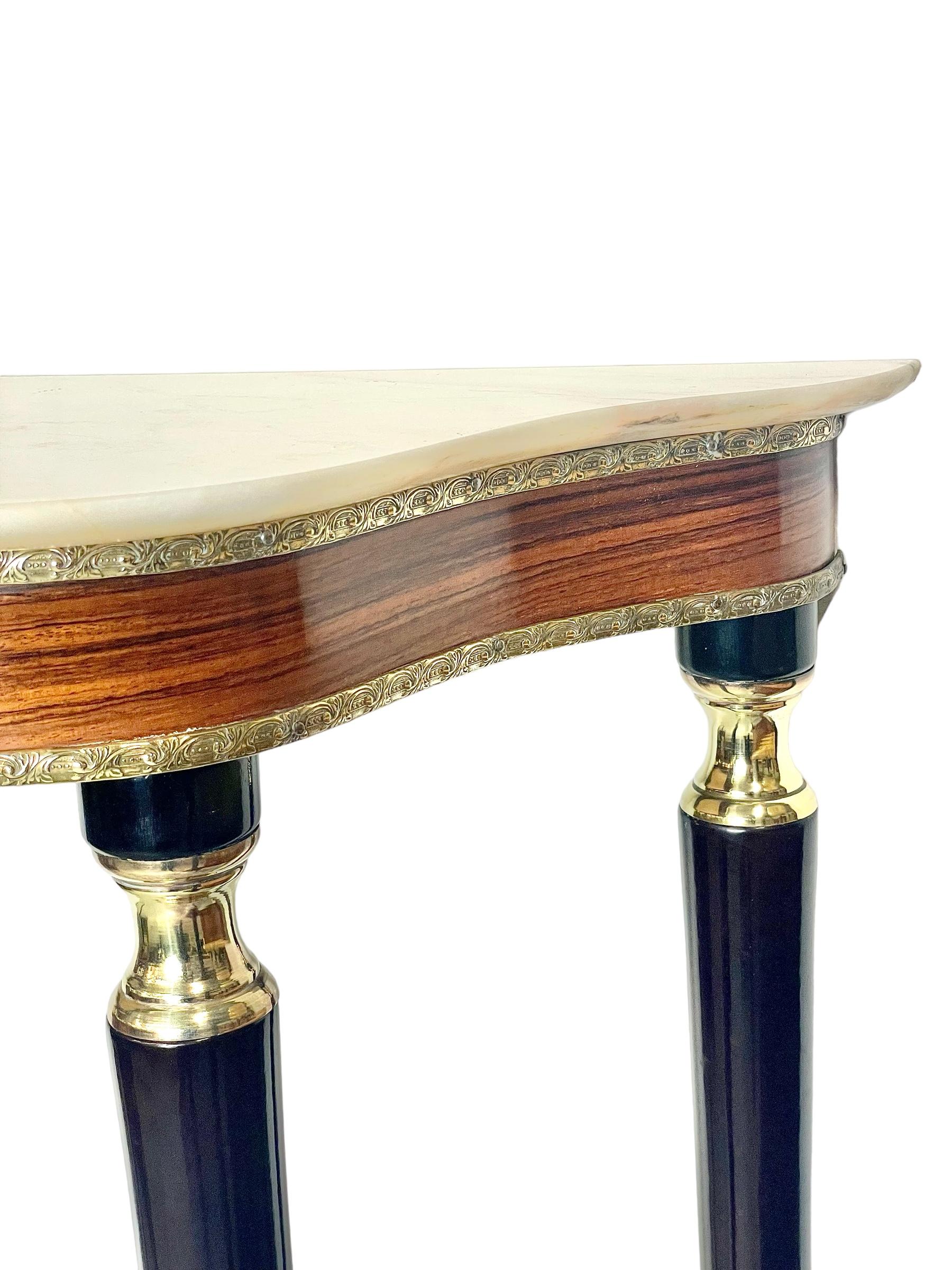 A striking Louis XVI style console table, with a shaped and polished creamy-white marble top. This freestanding table is raised on four tapering, ebonised legs, inset at the top with gleaming brass capitals, and terminating in gilt brass sabot feet.