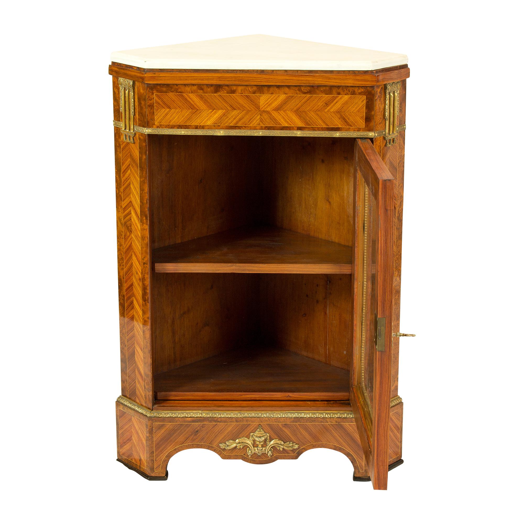 The corner cabinet comes from Paris, circa 1880 and was built in the style of Louis XVI, using walnut, frutiwooad and root wood. The top of the cabinet is finished with a white marble top. The corner cupboard is from Paris from the workshop/artist: