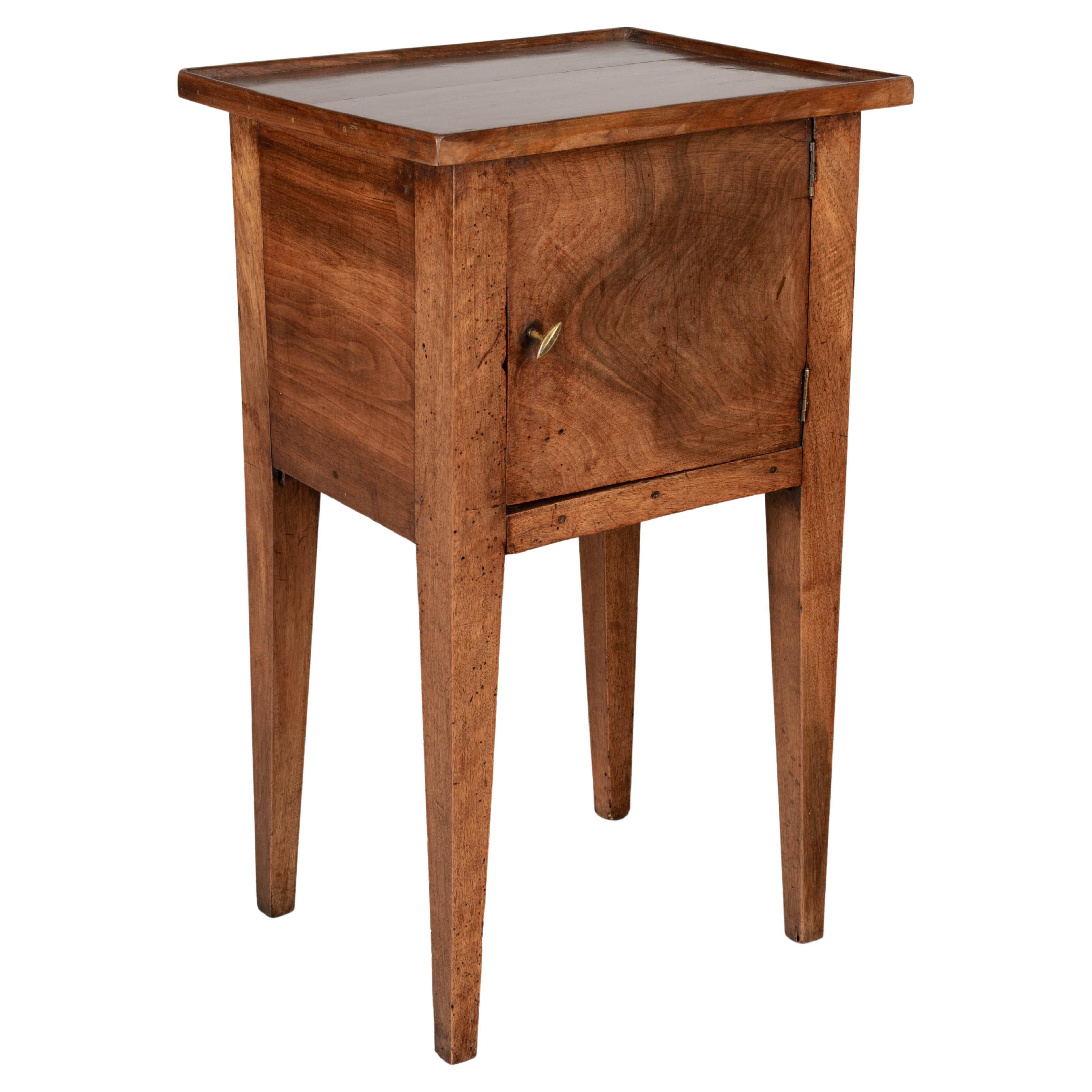An early 20th century Louis XVI style Country French side table, hand-crafted of solid walnut and finished on all four sides. Cabinet door with brass pull. Tapered legs. Newer top with gallery. Pegged construction. Good proportions for use as a