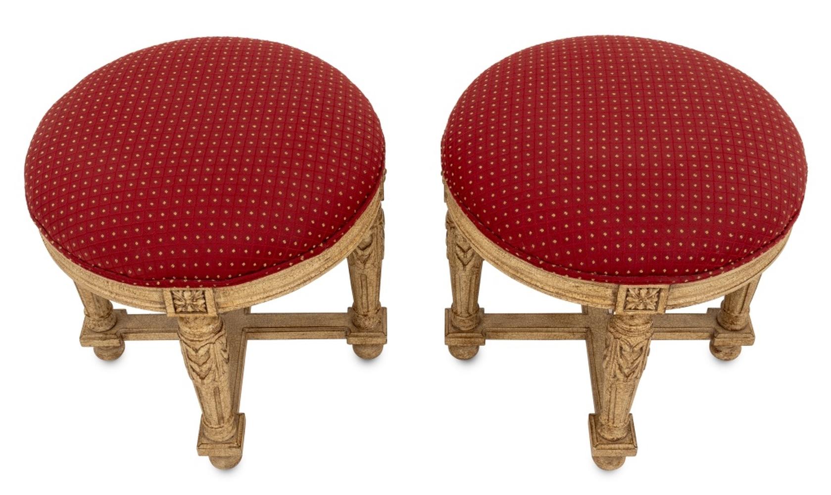Paire de tabourets de style Louis XVI peints en crème avec sièges rembourrés recouverts de tissu rouge et or sur quatre pieds sculptés réunis par une entretoise en X sur des pieds boules. 18.25