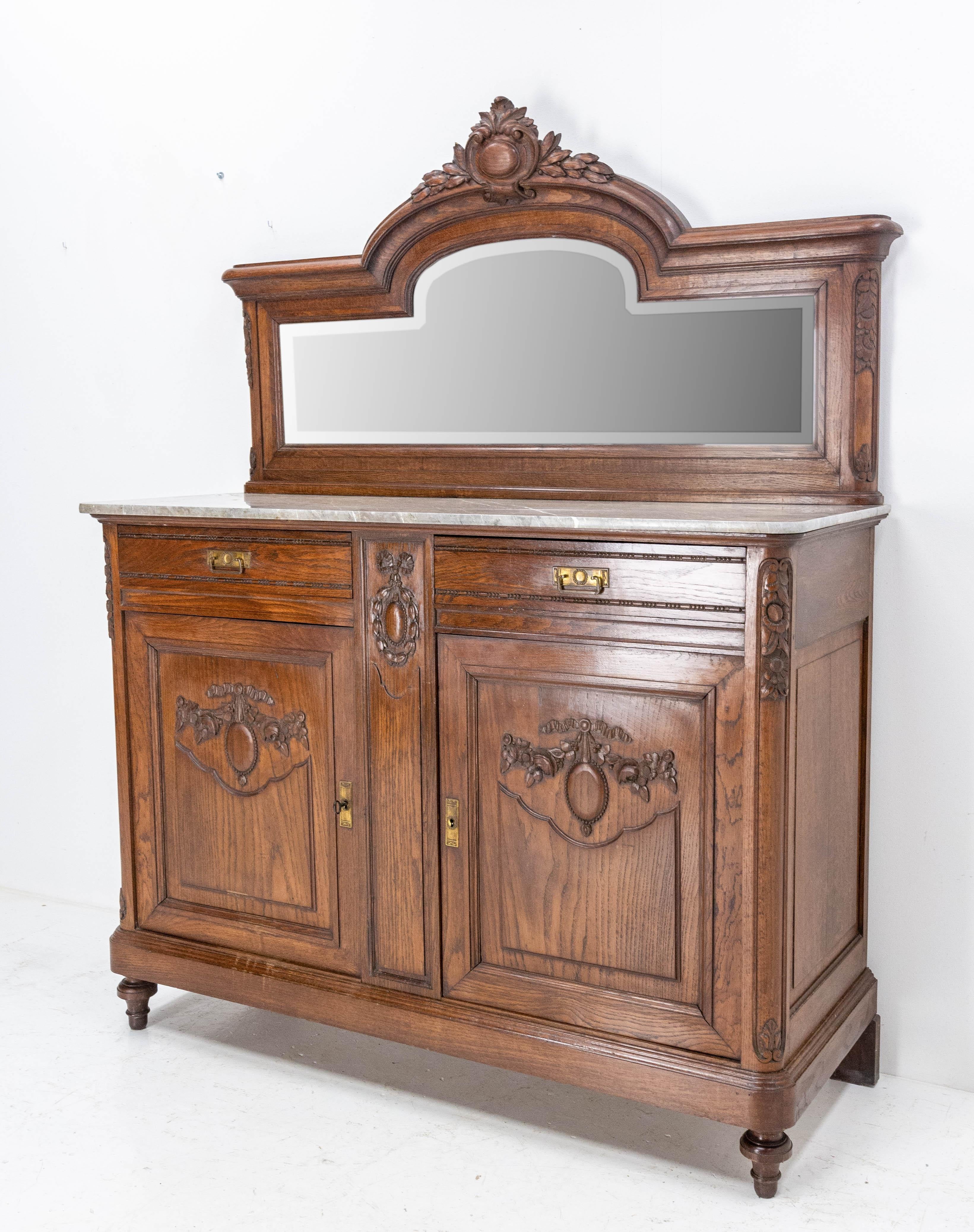 Credenza sideboard French dresser buffet, circa 1900.
Louis XVI style
Two drawers an two doors, and one shelf inside.
Pale honey figured walnut panels.
Oak panels decorated with carved flowers and medallions 
Beveled glass
Grey marble streaked