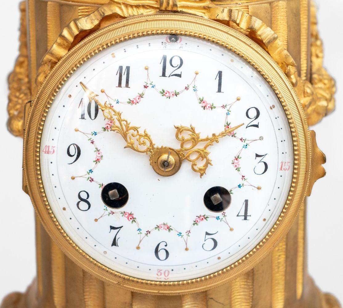 Pendule Cupidon en bronze patiné et doré de style Louis XVI, fin du XIXe siècle, le cadran circulaire peint à l'émail, avec mouvement à sonnerie, surmonté de Cupidon tirant sa flèche, sur une colonne cannelée avec des guirlandes feuillagées, sur un