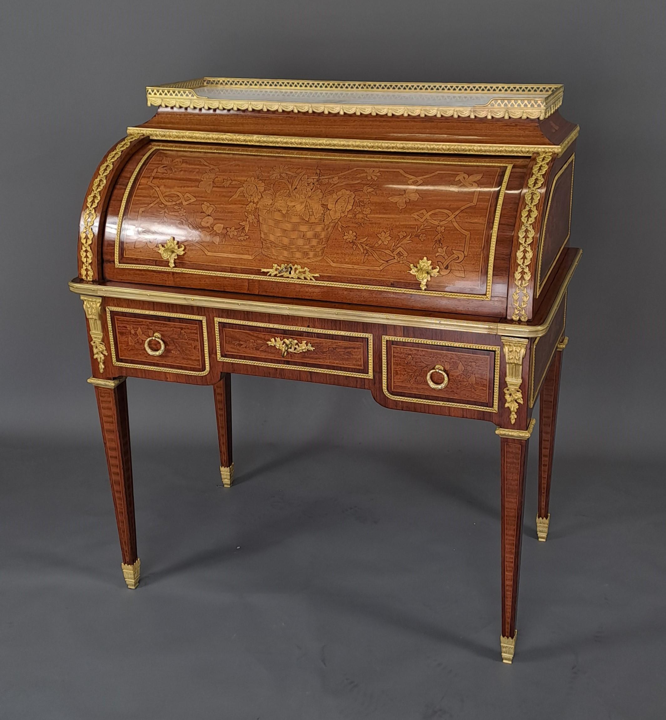 Elegantísimo secretario cilíndrico de estilo Luis XVI en marquetería de caoba y madera clara, con adornos florales en forma de cesta en la parte frontal del cilindro y arreglos florales en los laterales y cajones.
Rica ornamentación de bronce