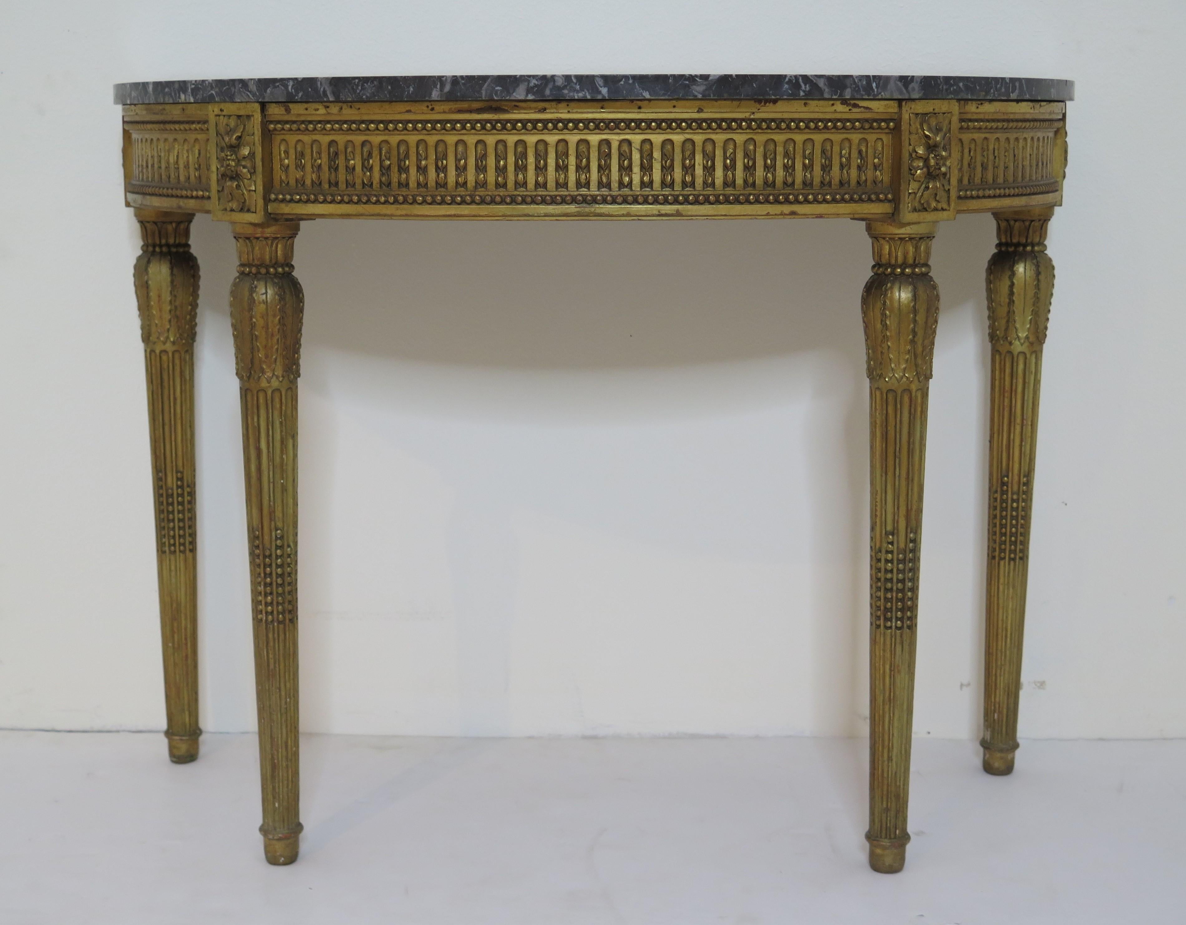 A Louis XVI style demilune console table with grey and white marble top. Ball and tooth finished apron with flower blocks. Leaf designed capitals above tapered and fluted legs. Excellently carved and decorated.