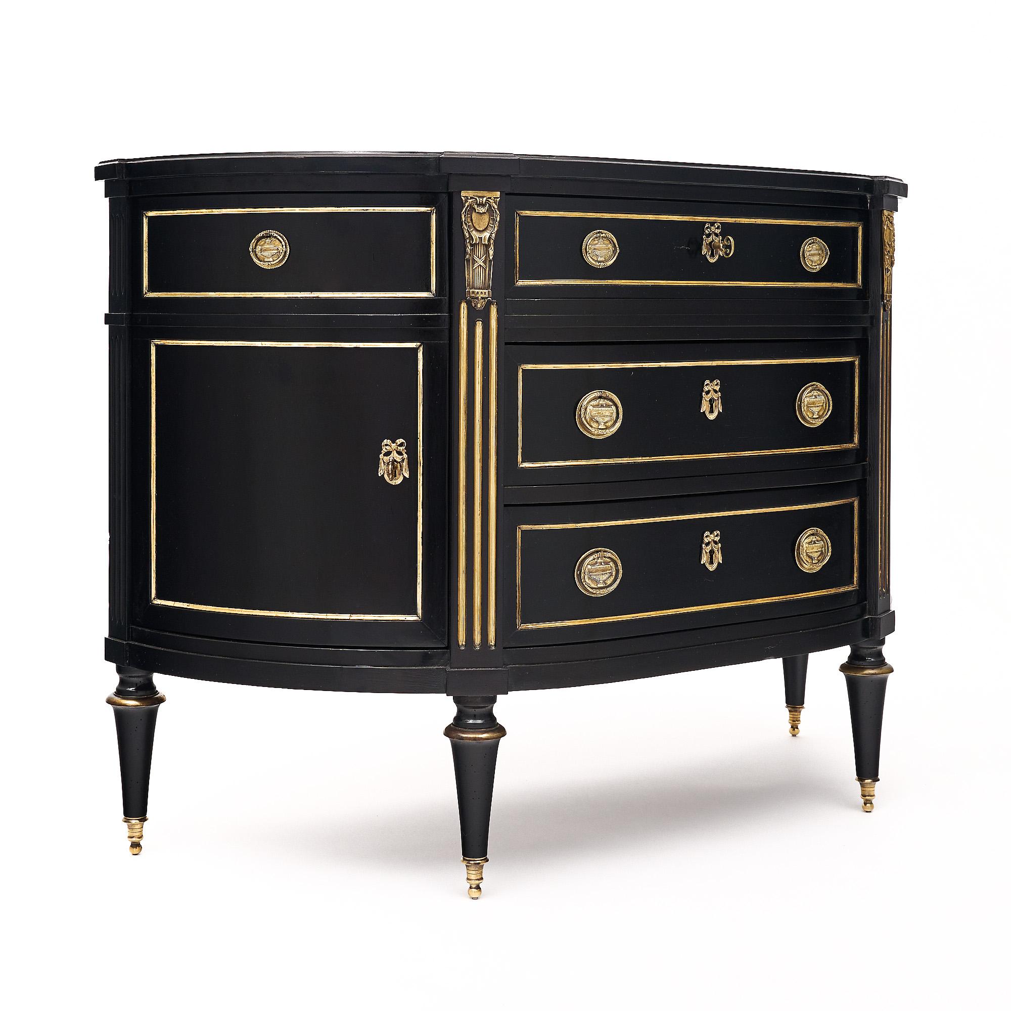 Chest of drawers from France in the Louis XVI Style. This piece is made of mahogany that has been ebonized and finished with a lustrous French polish finish of museum-quality. There are three dovetailed drawers in the center and two curved doors on