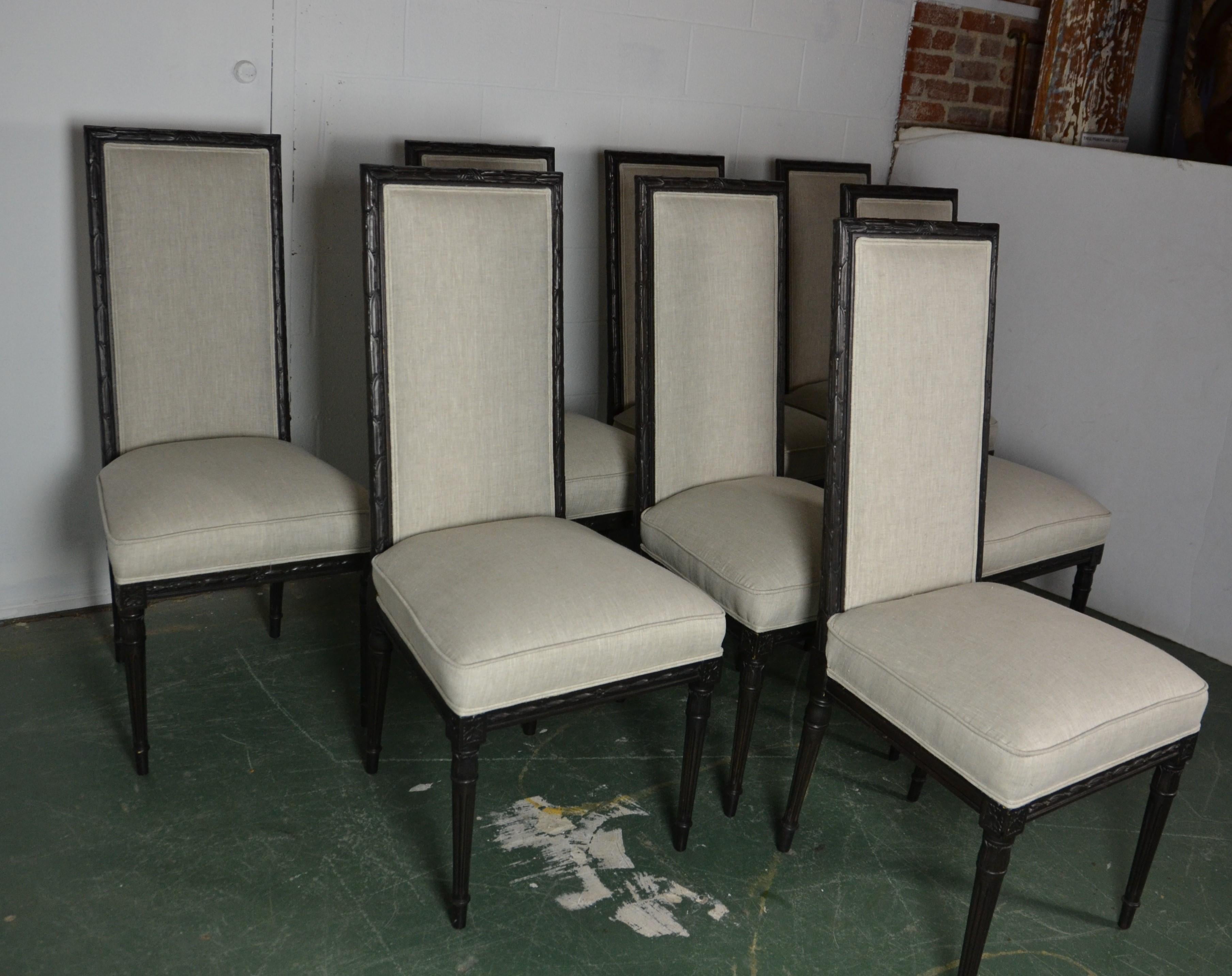 Set of eight Louis XVI style dining chairs. Upholstered in light gray linen. The frame is a black finish.