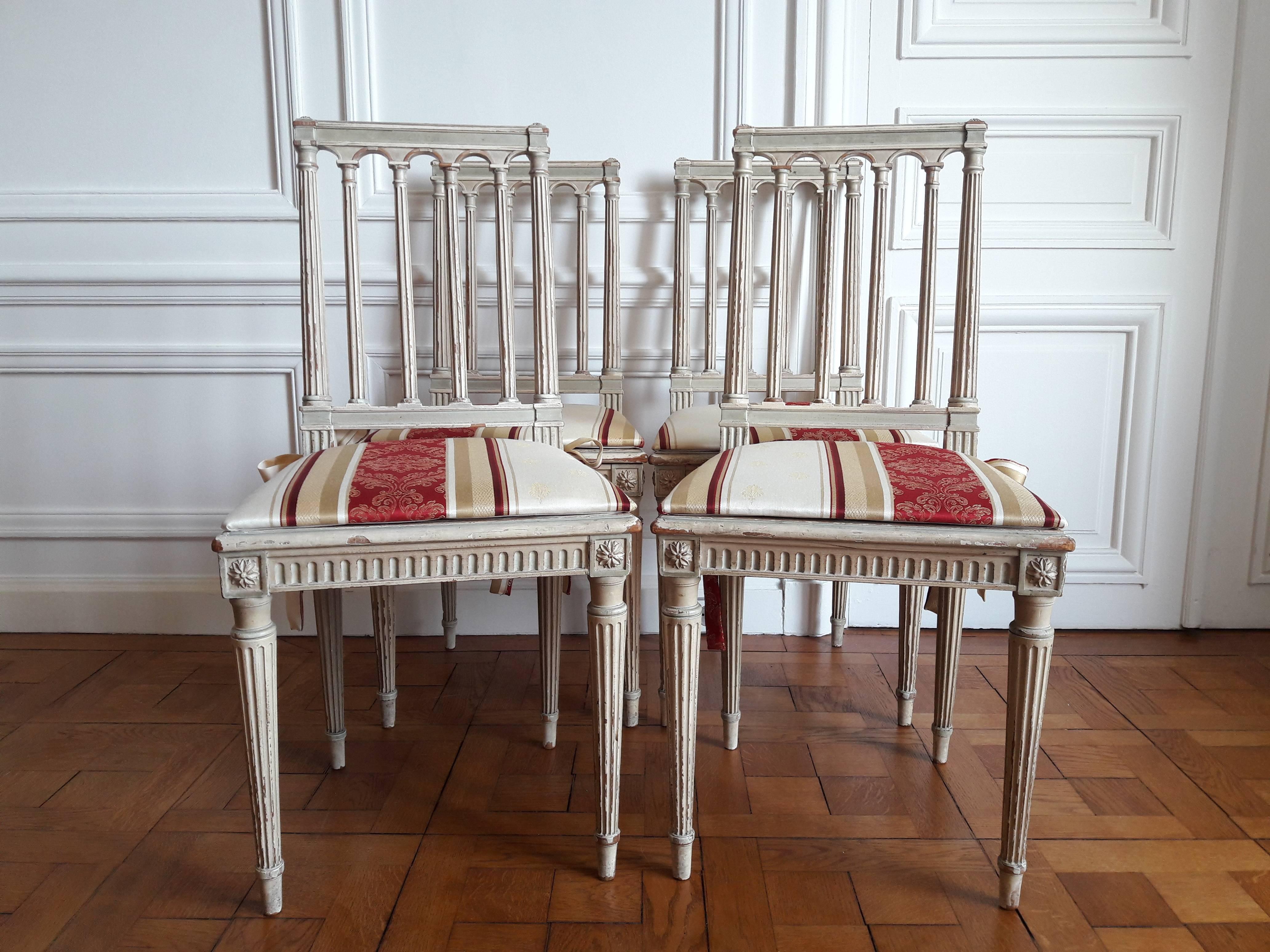 Set of four Louis XVI style chairs. The folders are formed by fluted columns and the seats are caned. 
There are also four sitting tops. The fabric is new, in beige, gold and red tones, with knots made in the same fabric to attach the tops to the