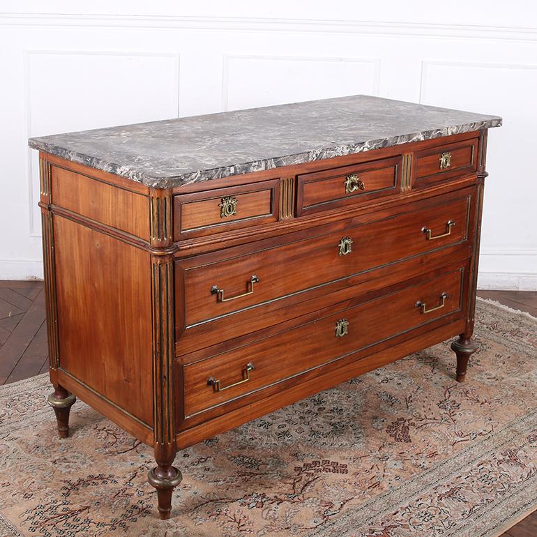 A very fine early 19th century Louis XVI Style Directoire commode from France. A shaped “Gris Sainte Anne” marble top with rounded front corners and a beveled edge sits above three short and two long paneled drawers. The rectangular panels are