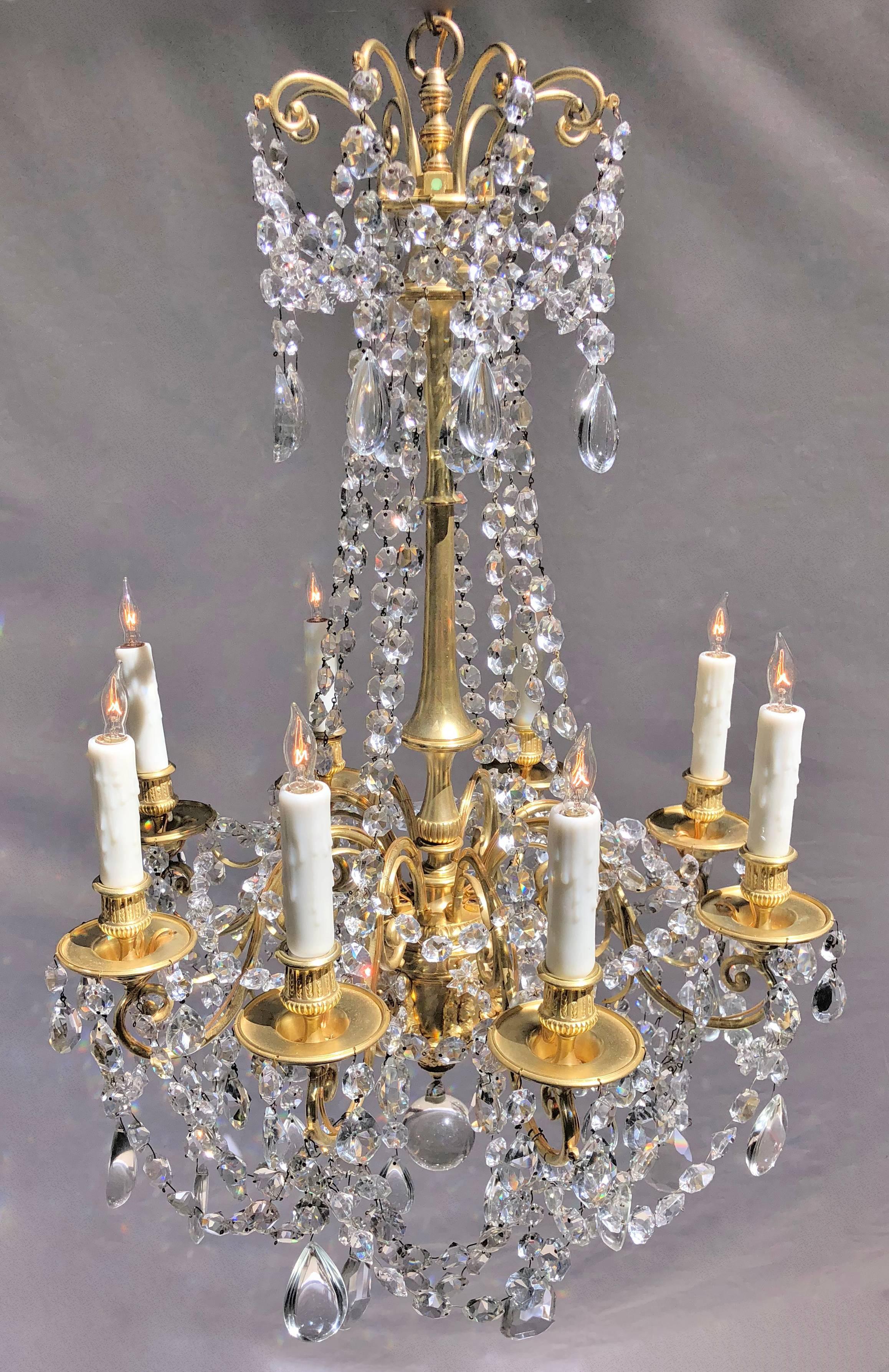 This Louis XVI chandelier was originally candle and has since been rewired and electrified. The crown has eight bronze scrolls with swaged crystal chains. Bronze center column comes down to console holding eight solid bronze scrolled arms with