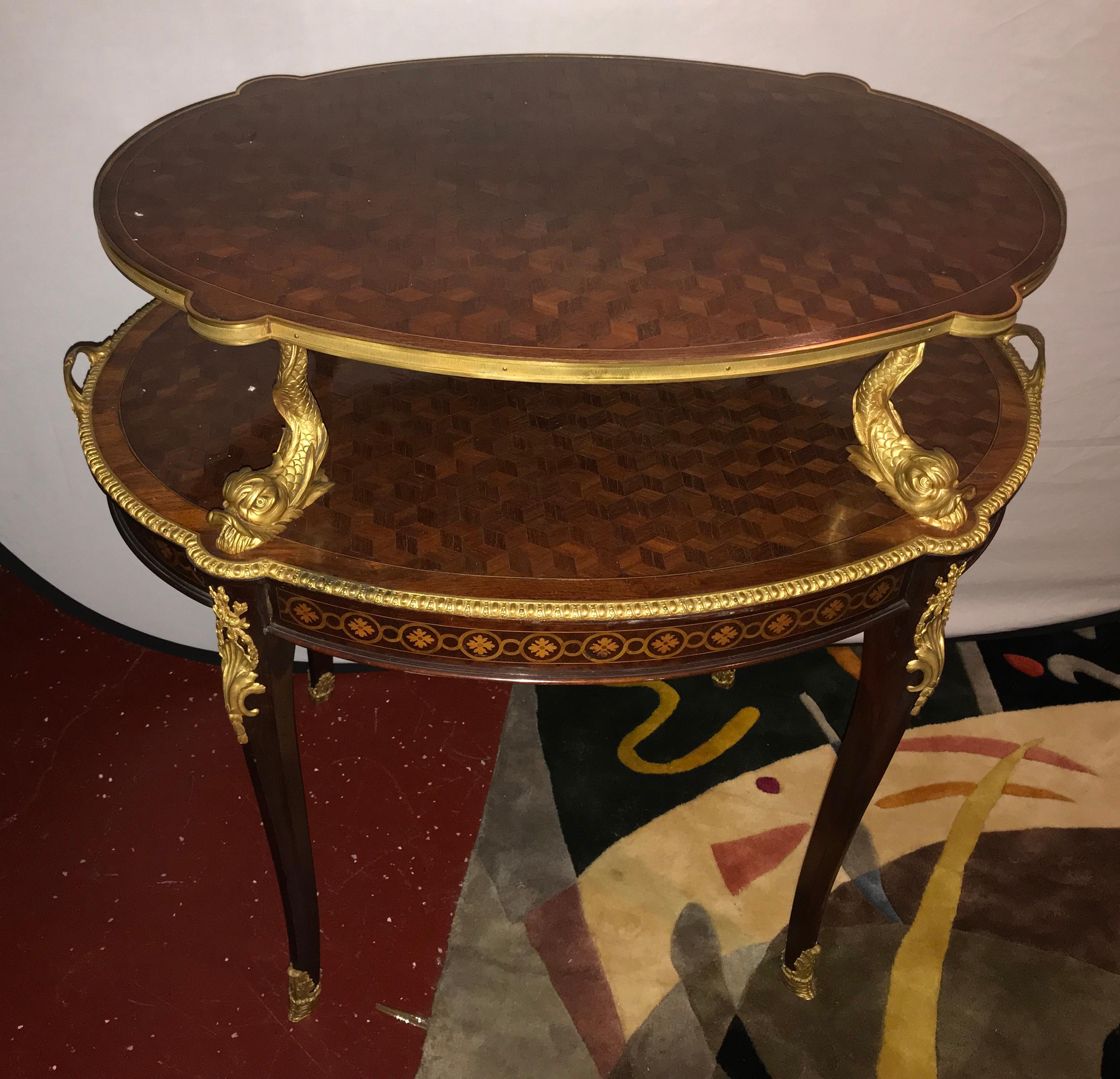 A Louis XVI style doré bronze figural mounted deseret two-tier serving stand. This finely cast late 19th-early 20th century serving table is simply the finest quality in regards to casting and finish. The full bodied dolphins separating the two
