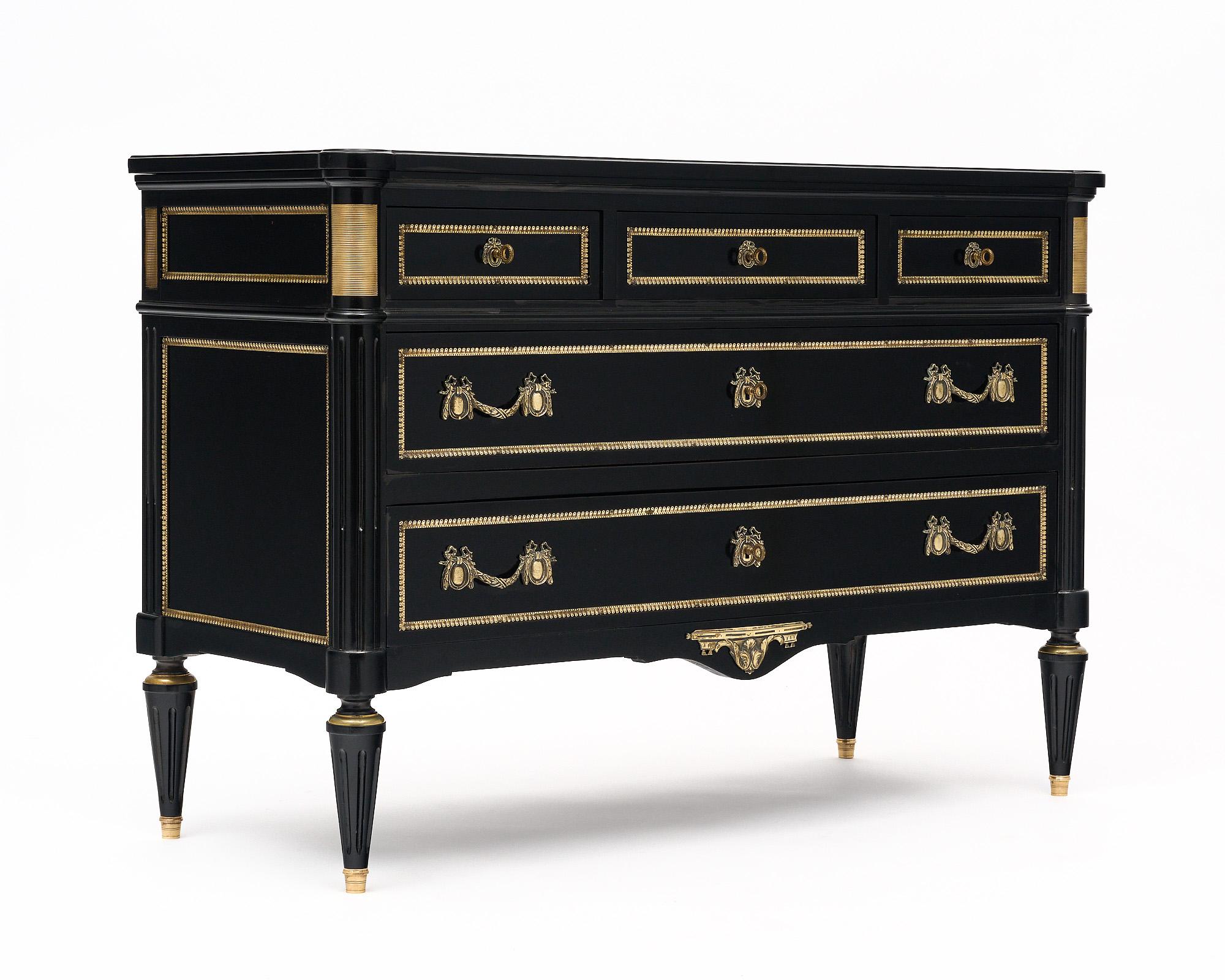 Chest of drawers from France in the Louis XVI style and featuring elaborate cast brass trim, hardware, and detailing throughout. This piece has been ebonized and finished with a lustrous French polish. There are three dovetailed drawers above two