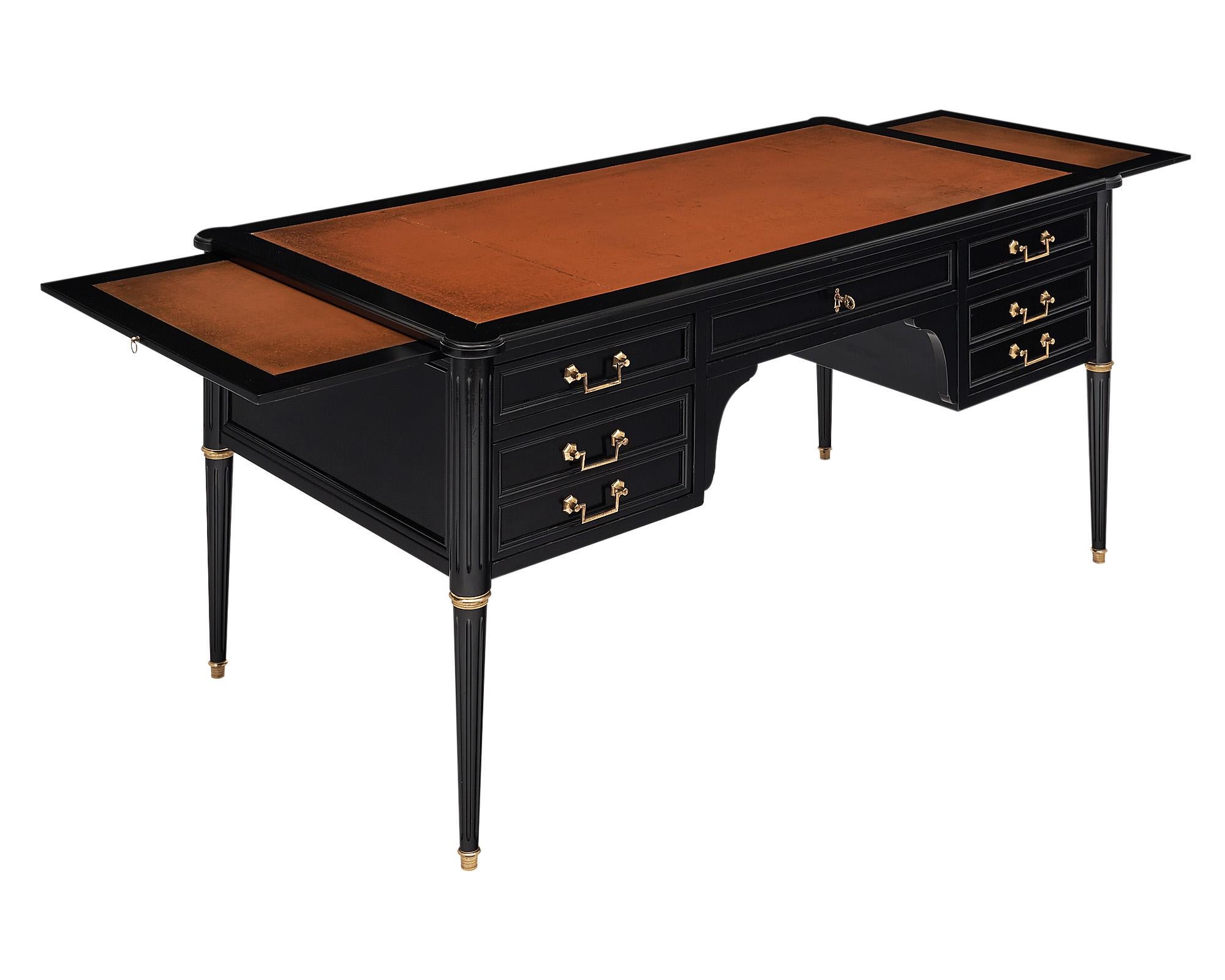 Desk, French, in the Louis XVI style with the original leather top and striking tapered and fluted legs. The important desk features ample storage inside the dovetailed drawers and additional pull out extension tablets. Each leaf/tablet adds an