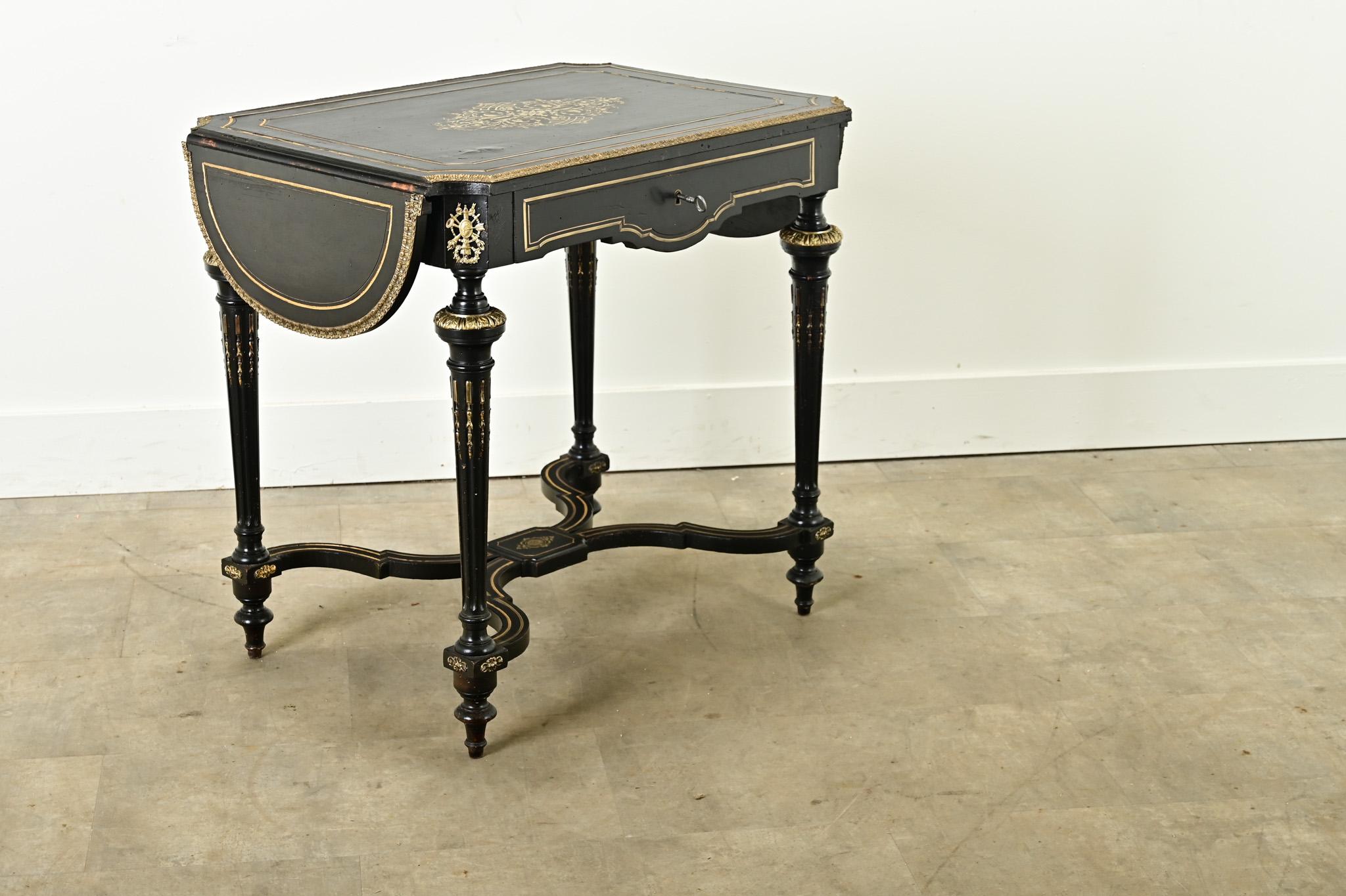 A French Louis XVI style ebonized and brass inlay drop leaf desk. This desk has brass ormolu and inlay banding throughout with a brass inlaid cartouche in the center of its top. Both sides of the desk have demilune drop leaves supported by wooden