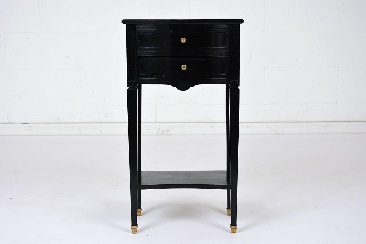 This 1970s Louis XVI style nightstand is made of mahogany wood with an ebonized and lacquered finish. The nightstand has two drawers with curved fronts and simple brass drawer pulls. Stabilizing the tape1ed legs is an open shelf for extra storage.
