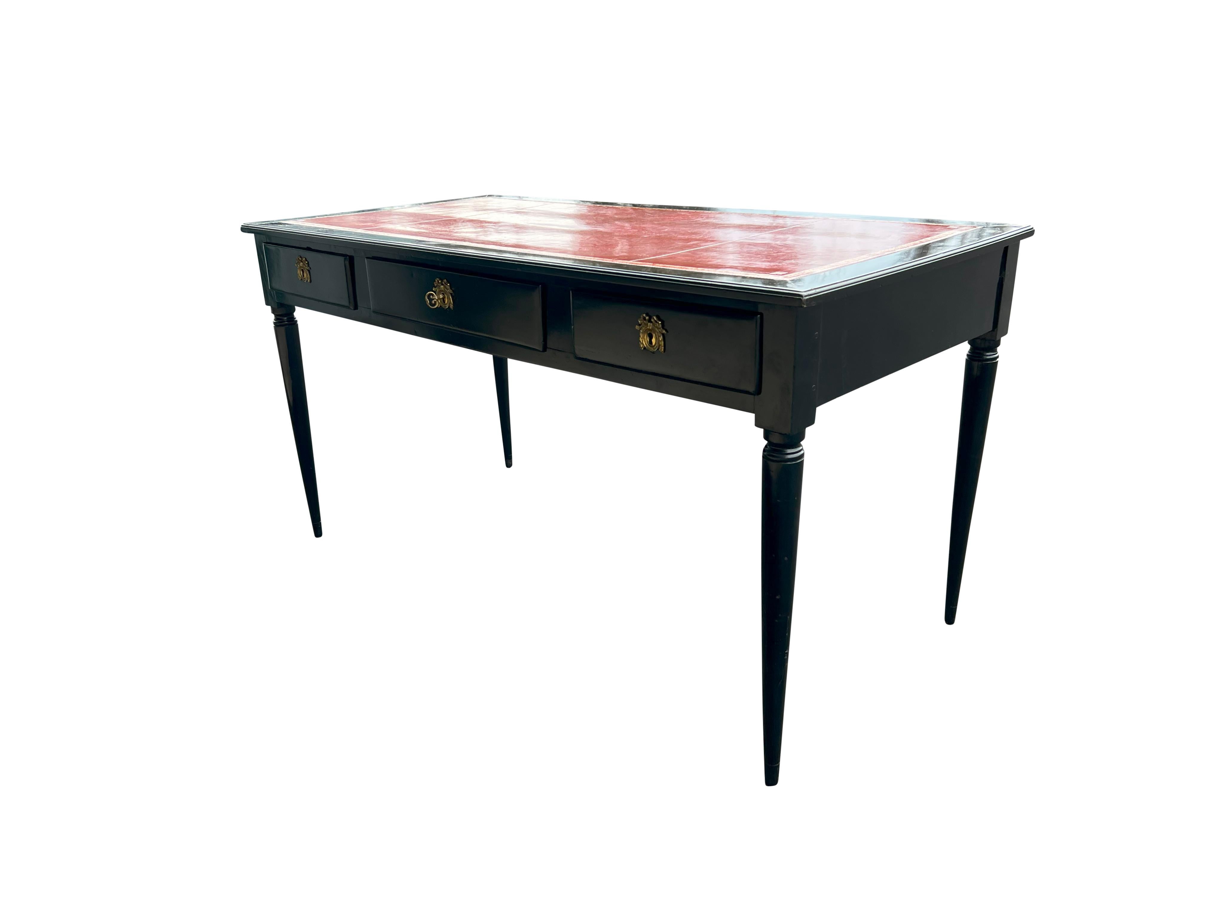 With rectangular red leather inset top within a conforming border over three drawers and three opposing false drawers. With circular tapered legs. Key.