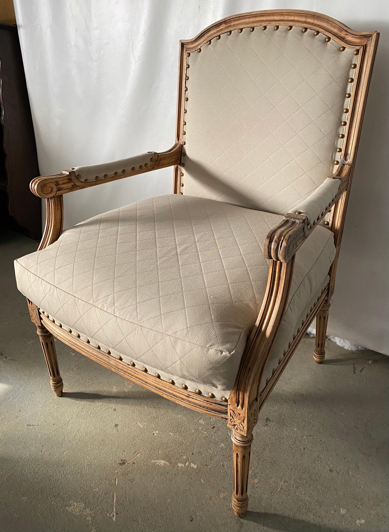 Elegant French Louis XVI style armchair with complementary side chair in bleached wood frames, fluted leg and cubic blocks decorated with florets, upholstered in classic beige quilted fabric. Appropriate for dining, desk or vanity chair in a modern,