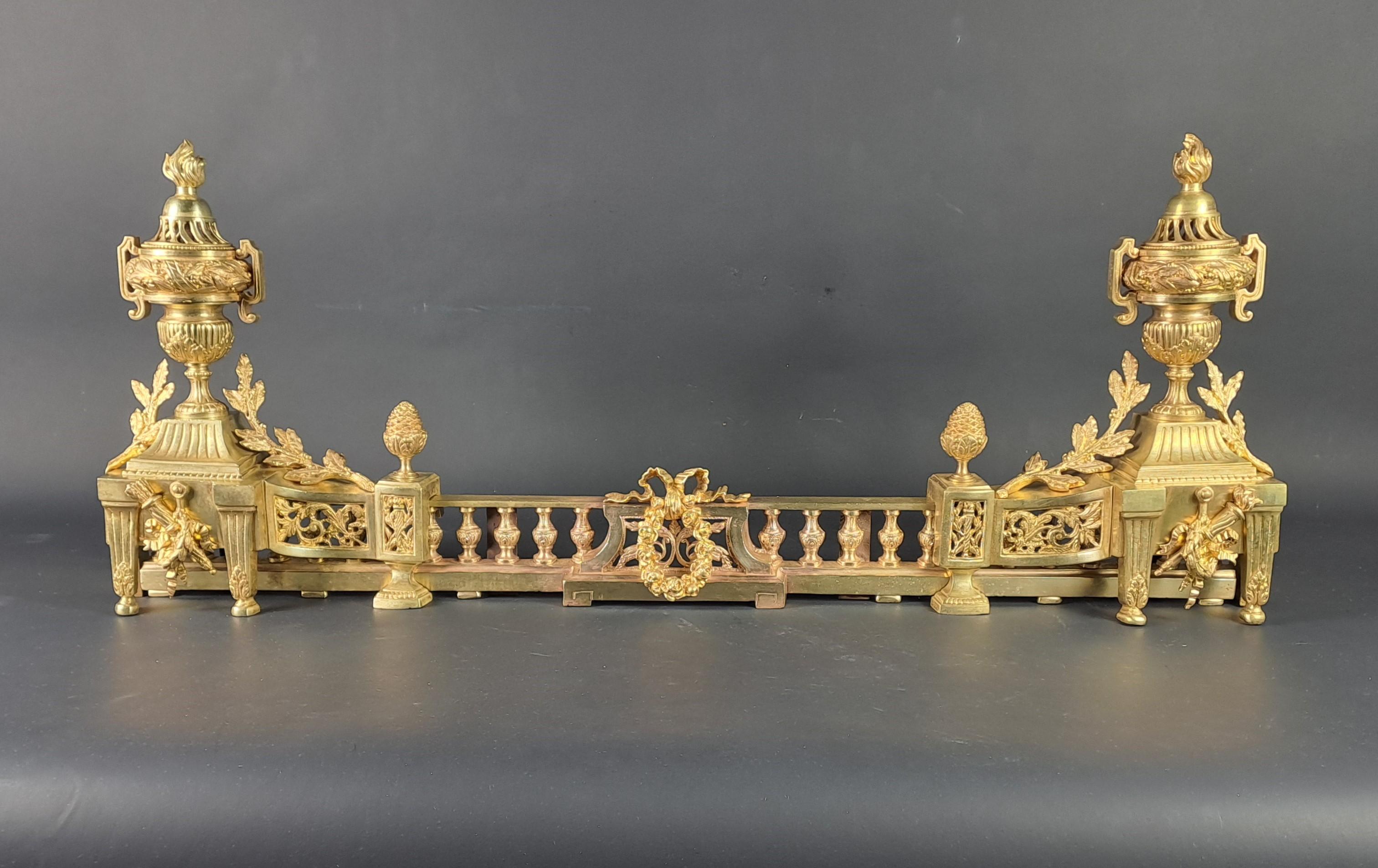 Beautiful Louis XVI style fire bar in finely chiseled gilt bronze with rich decoration of fire pots, pinnacle in the shape of pine cones and foliage.

Composed of two modules connected to each other by a baluster barrier which can slide and thus